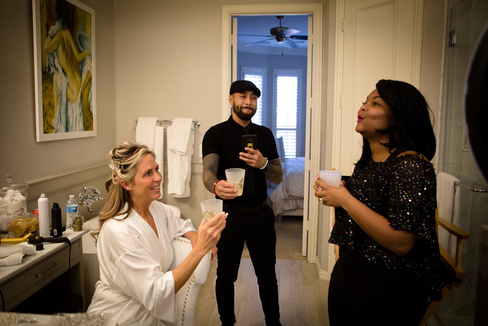A man and two women are standing in a bathroom.