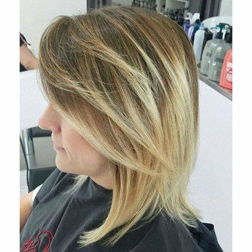 A woman with blonde hair is sitting in a chair in a salon.