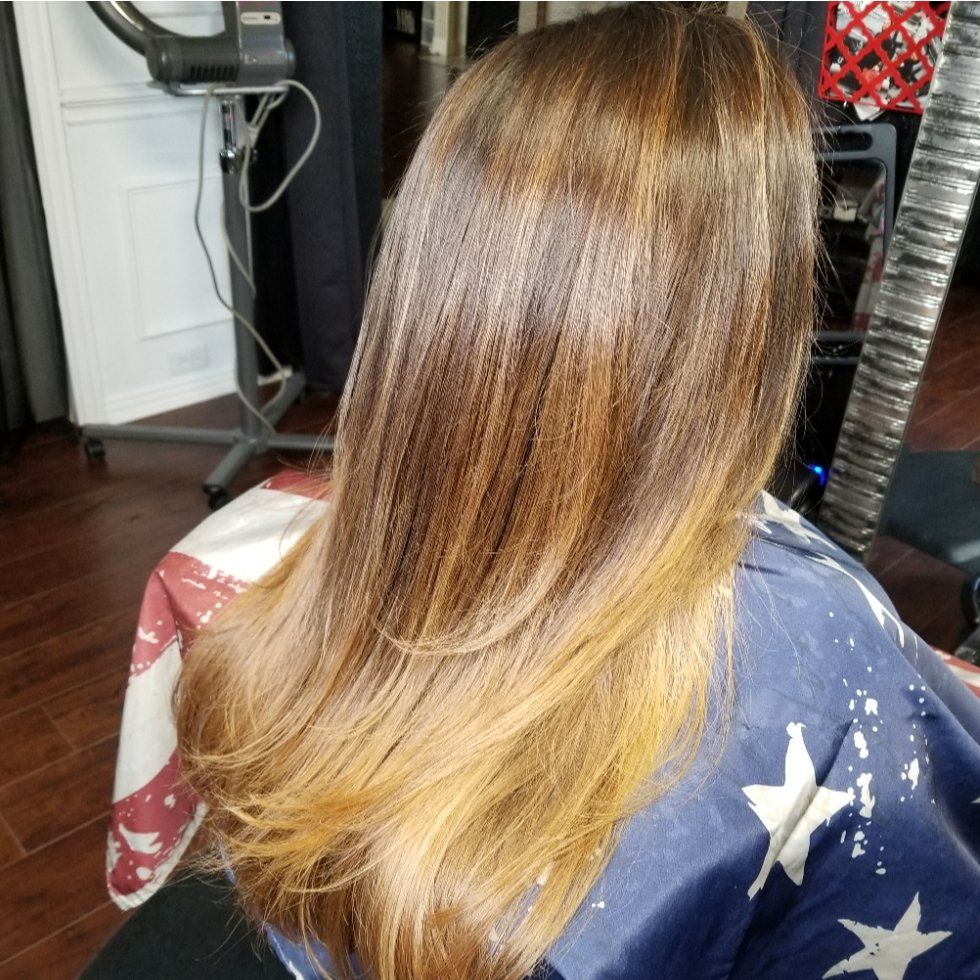 A woman with long hair is sitting in a chair in a salon.