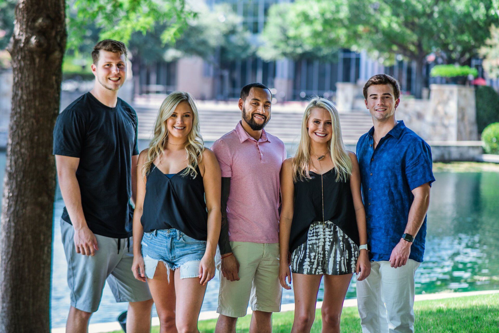 A group of people are standing next to each other in front of a lake.