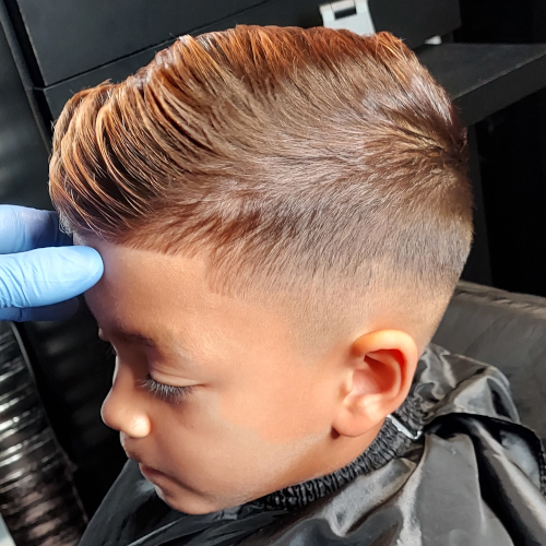 A young boy is getting his hair cut by a barber