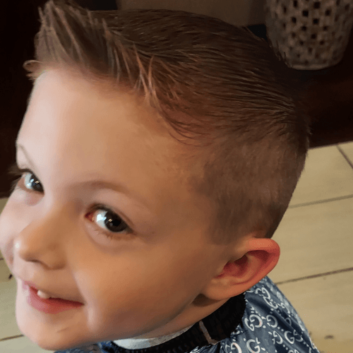 A young boy with a mohawk hairstyle is smiling