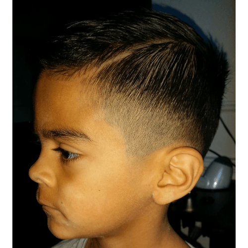A young boy with a very short haircut is looking at the camera.