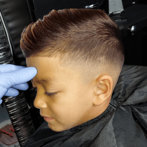 A young boy is getting his hair cut at a barber shop