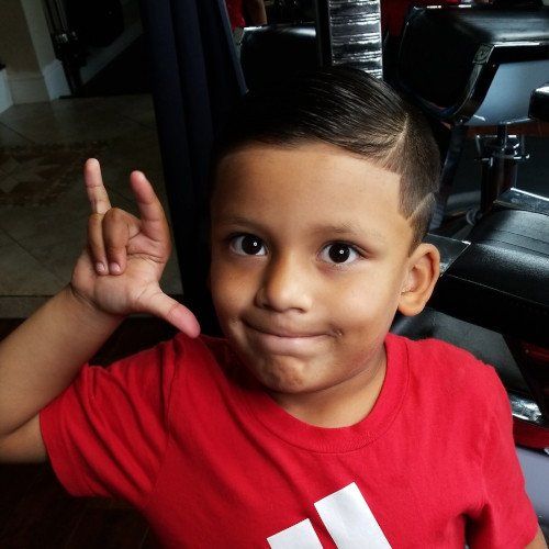 A young boy wearing a red adidas shirt giving the horns sign