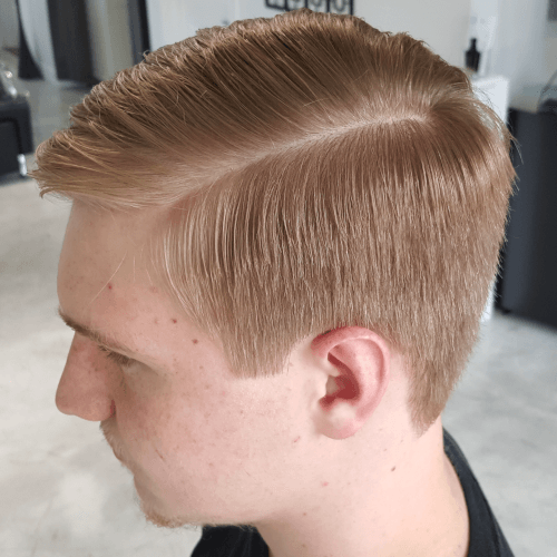 A young man is getting his hair cut in a salon.