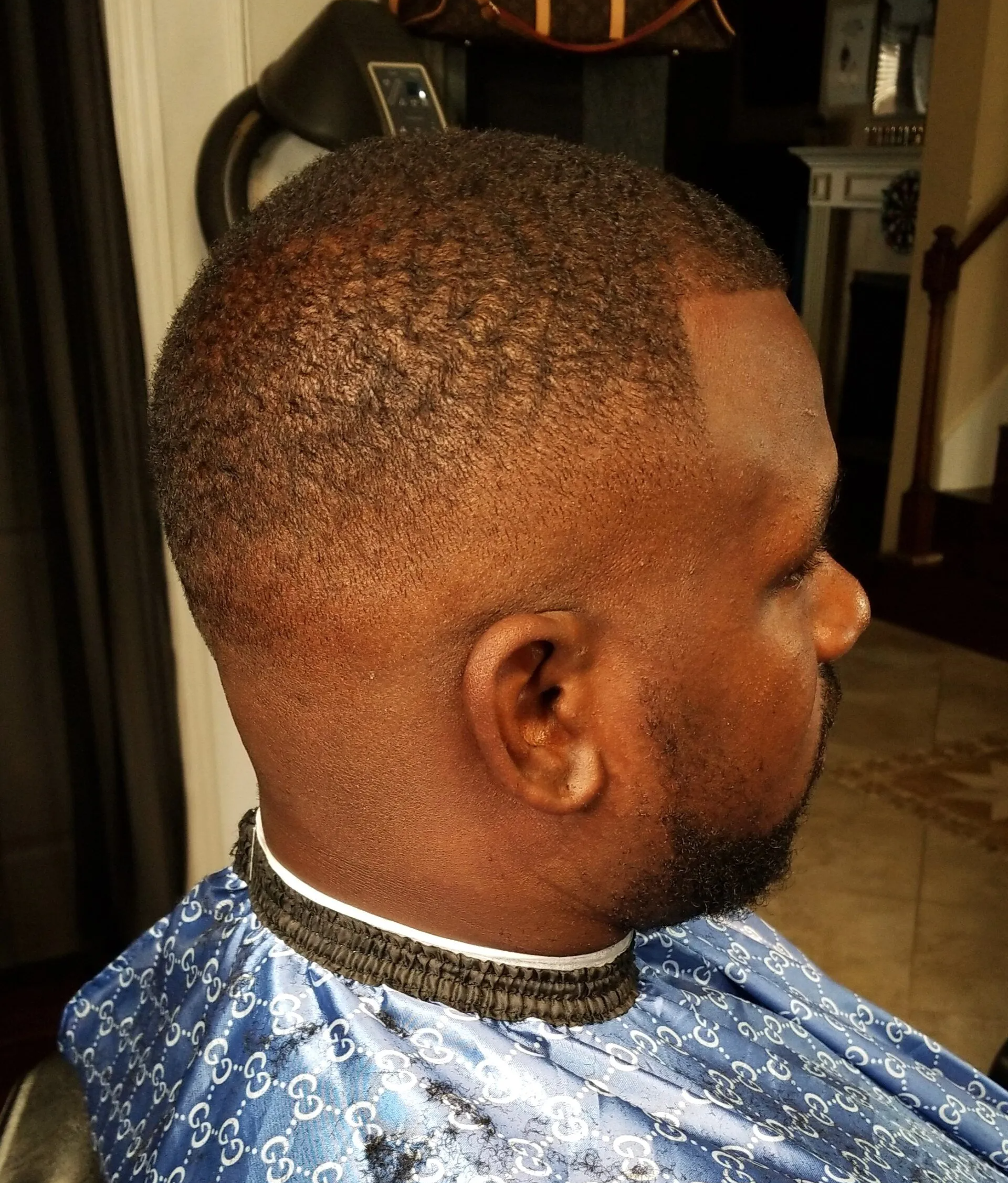 A man with a beard is getting his hair cut by a barber.