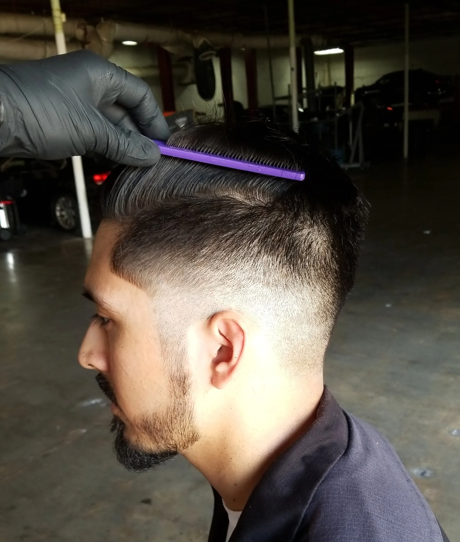 A man is getting his hair combed by a person wearing black gloves.