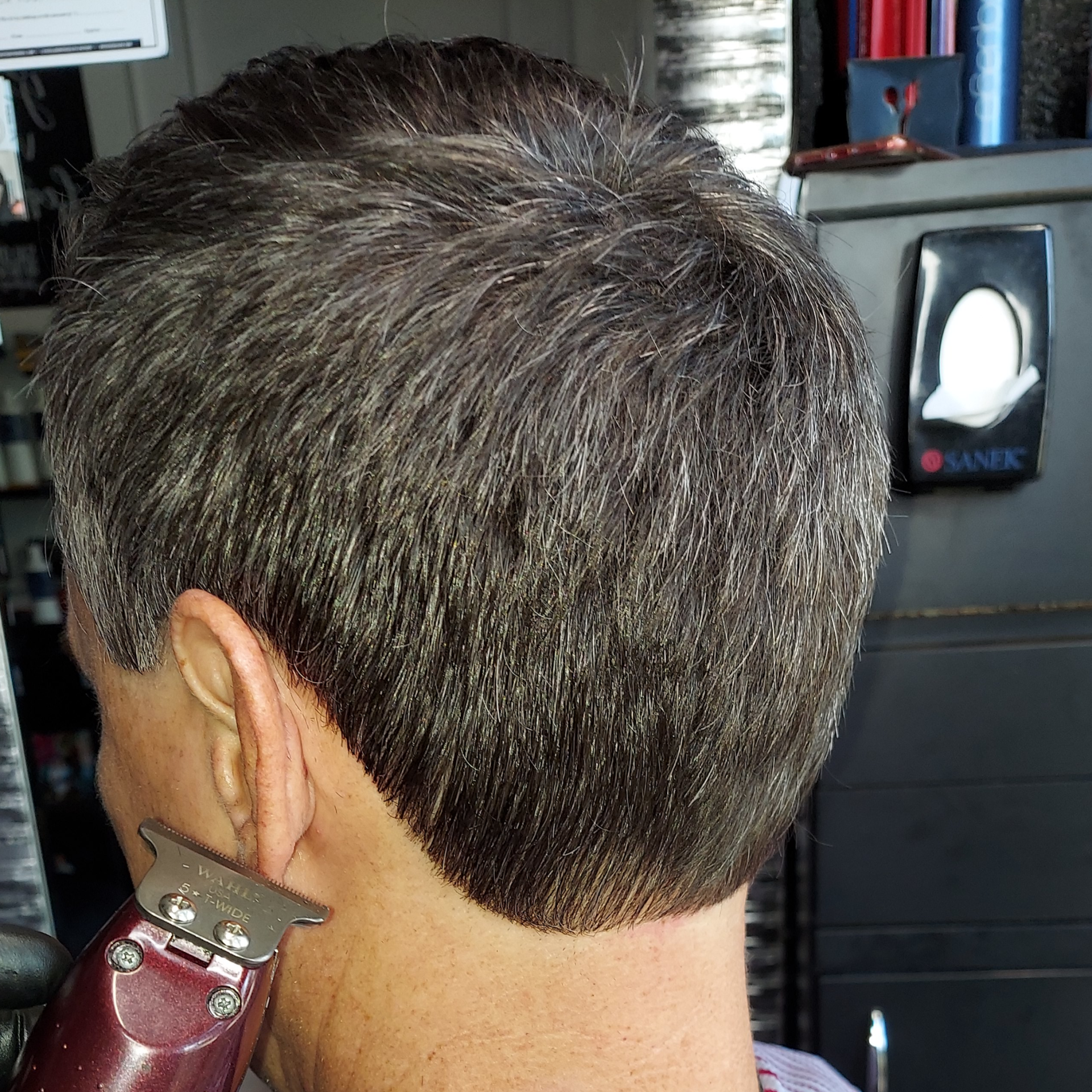 A man is getting his hair cut by a clipper