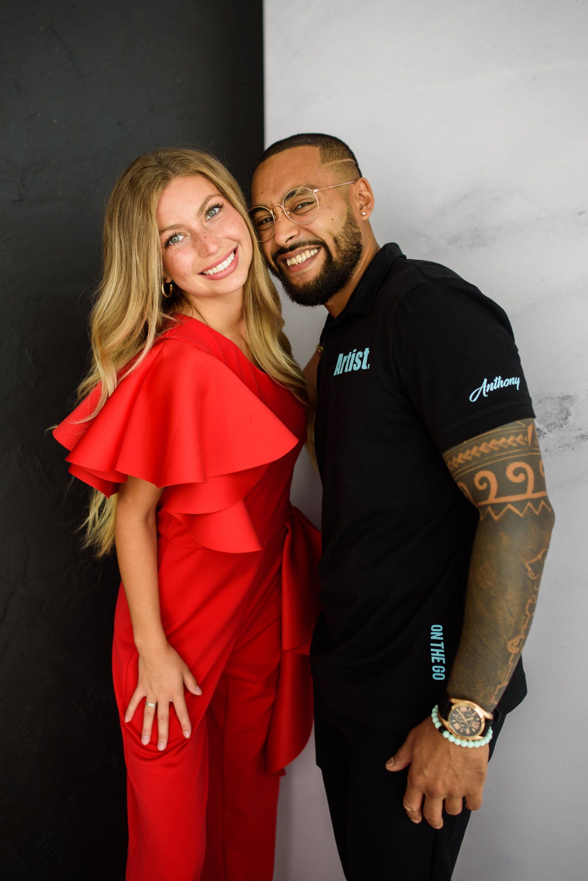 A man and a woman are posing for a picture together . the woman is wearing a red dress.