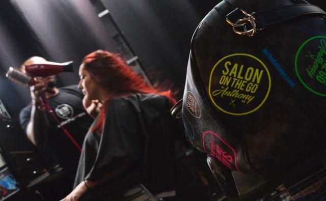 A man is blow drying a woman 's hair in a salon on the go.