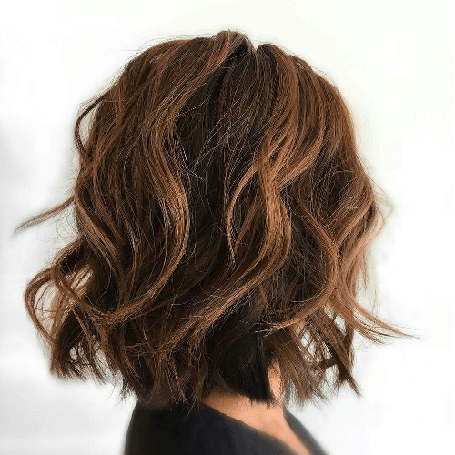 A woman with short wavy brown hair is wearing a black shirt.