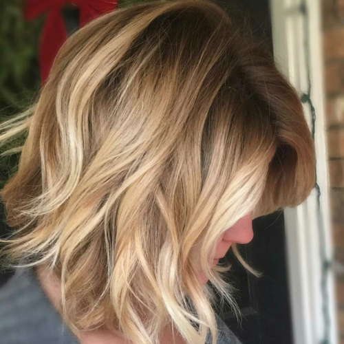 A woman with blonde hair is standing in front of a door.