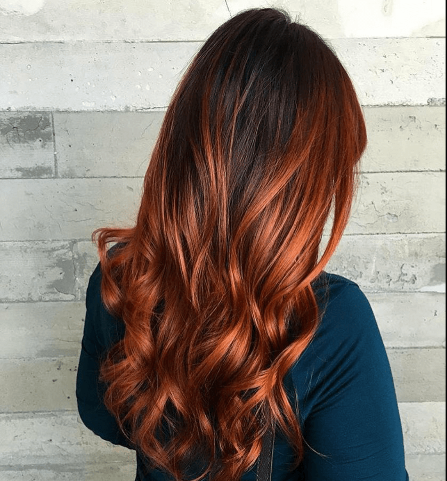 A woman with long red hair is wearing a blue shirt.