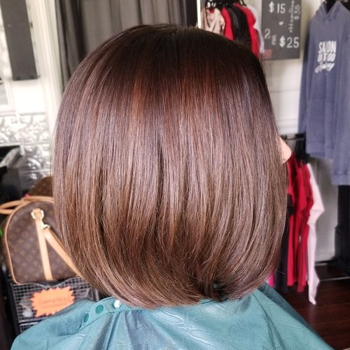 A woman in a green cape is getting her hair cut