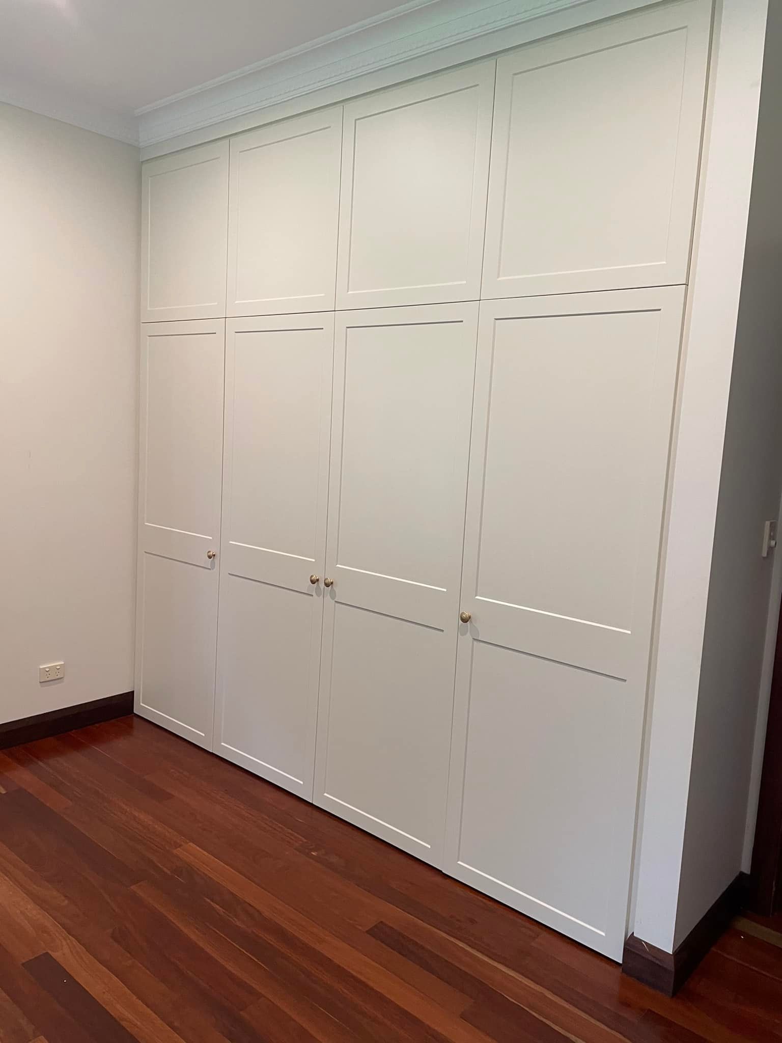 A Room With a Wooden Floor and White Cabinets — Cairns Custom Wardrobes in Manunda, QLD