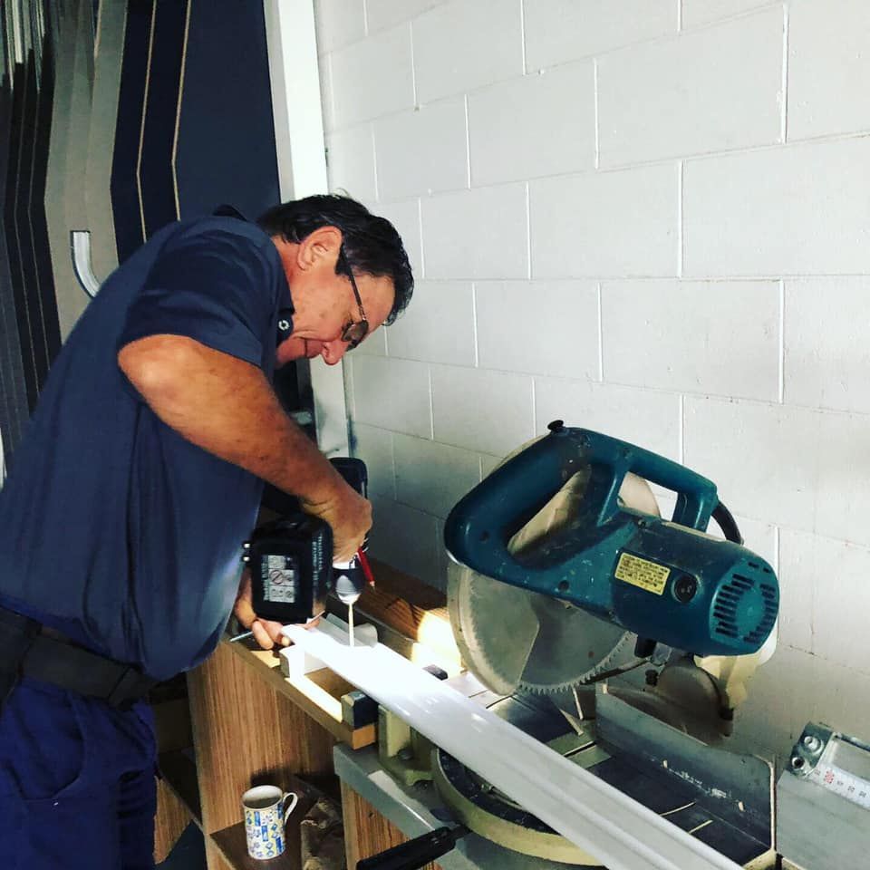 A Man is Using a Makita Circular Saw to Cut a Piece of Wood — Cairns Custom Wardrobes in Manunda, QLD