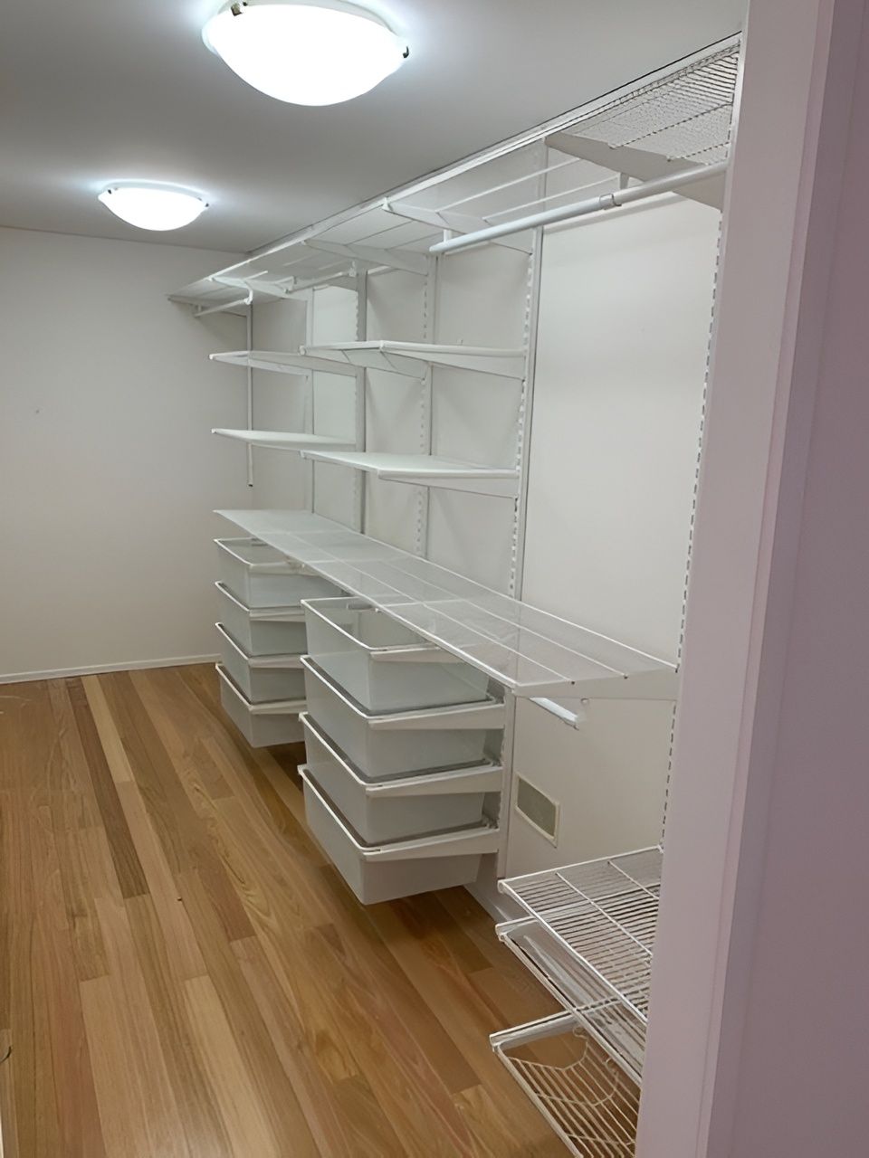 White Wire Shelving and Drawers in a Closet. Light Wood Floor and White Walls — Cairns Custom Wardrobes in Manunda, QLD