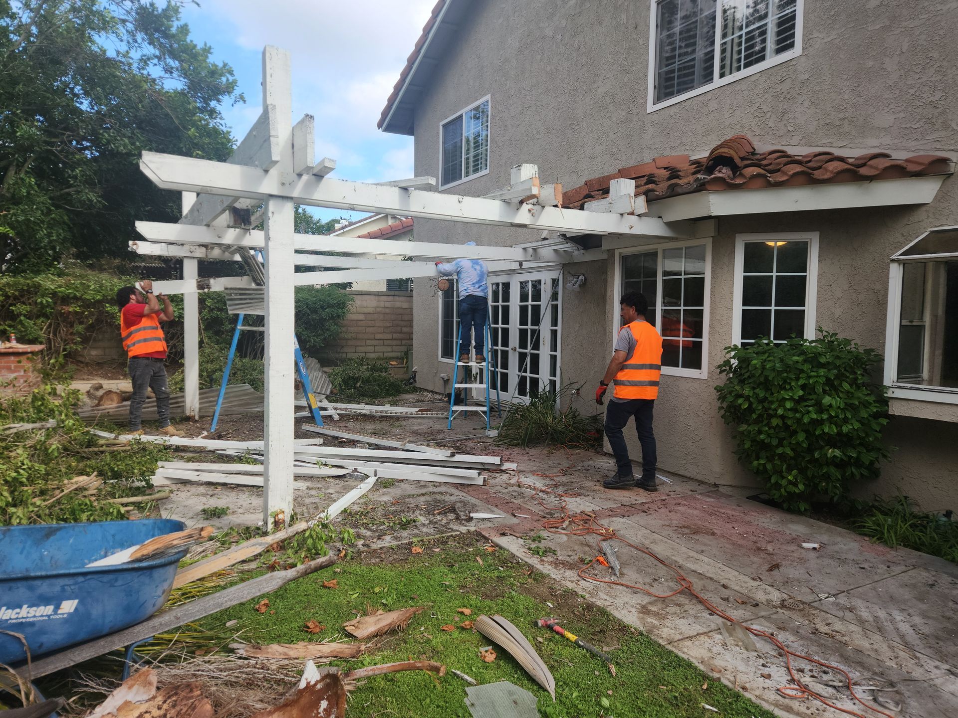 A group of men are working on a pergola in front of a house.