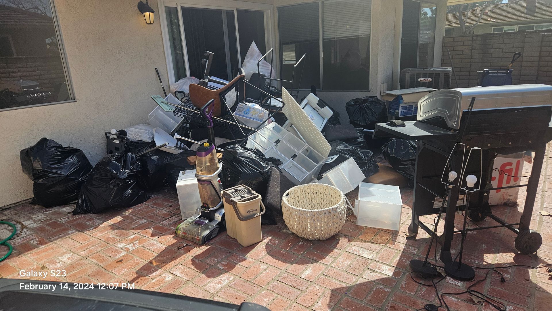 A pile of trash is sitting on the ground in front of a house.