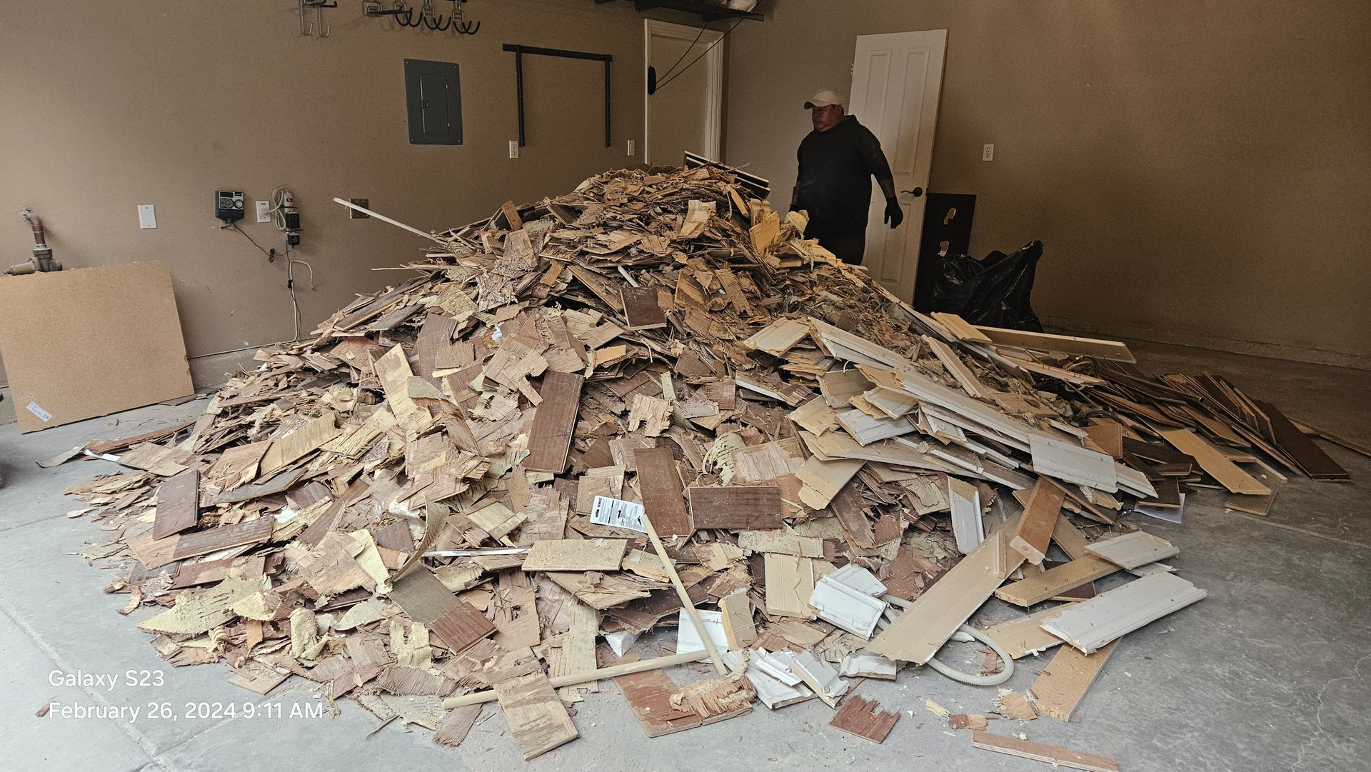 A man is standing next to a pile of wood in a garage.
