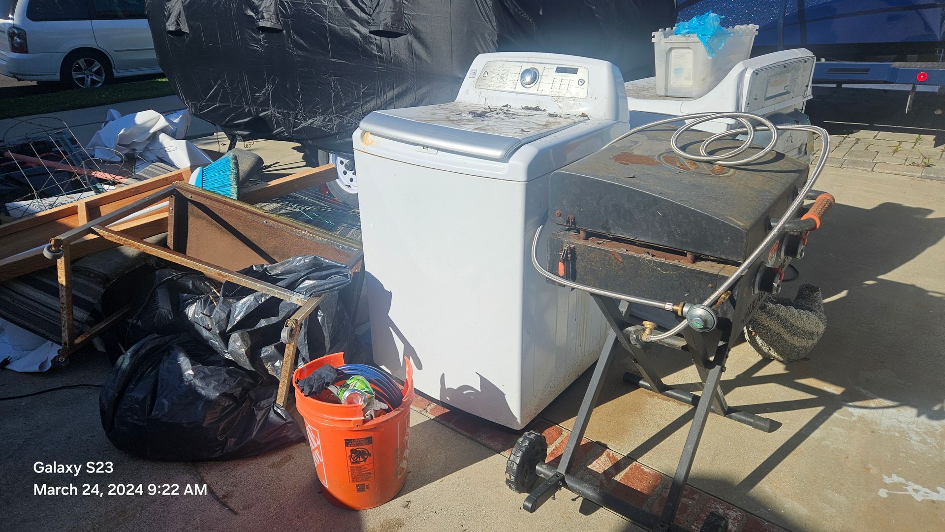 A washer and dryer are sitting in a pile of trash.