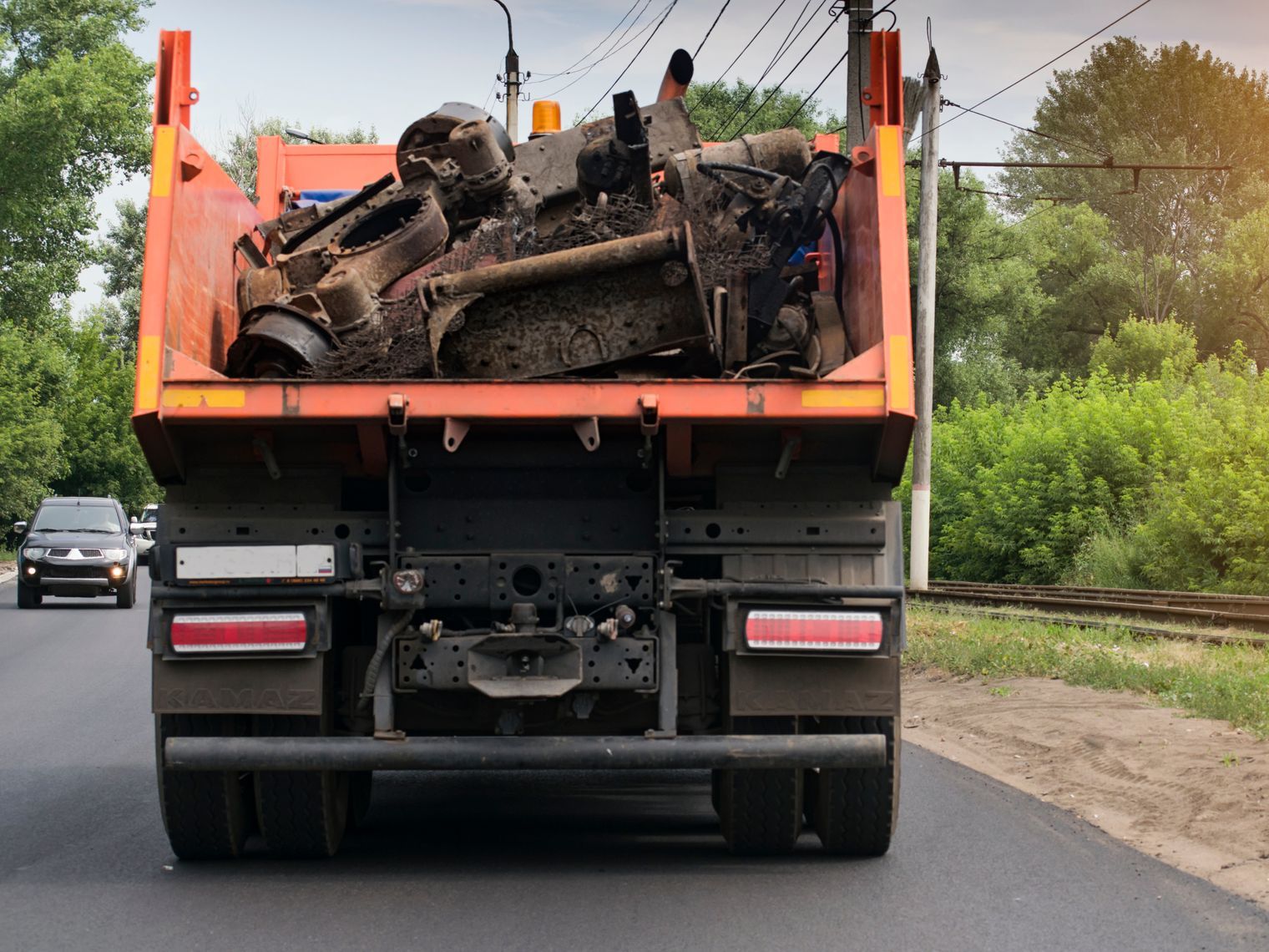 A dump truck is driving down a road with a lot of trash in the back.