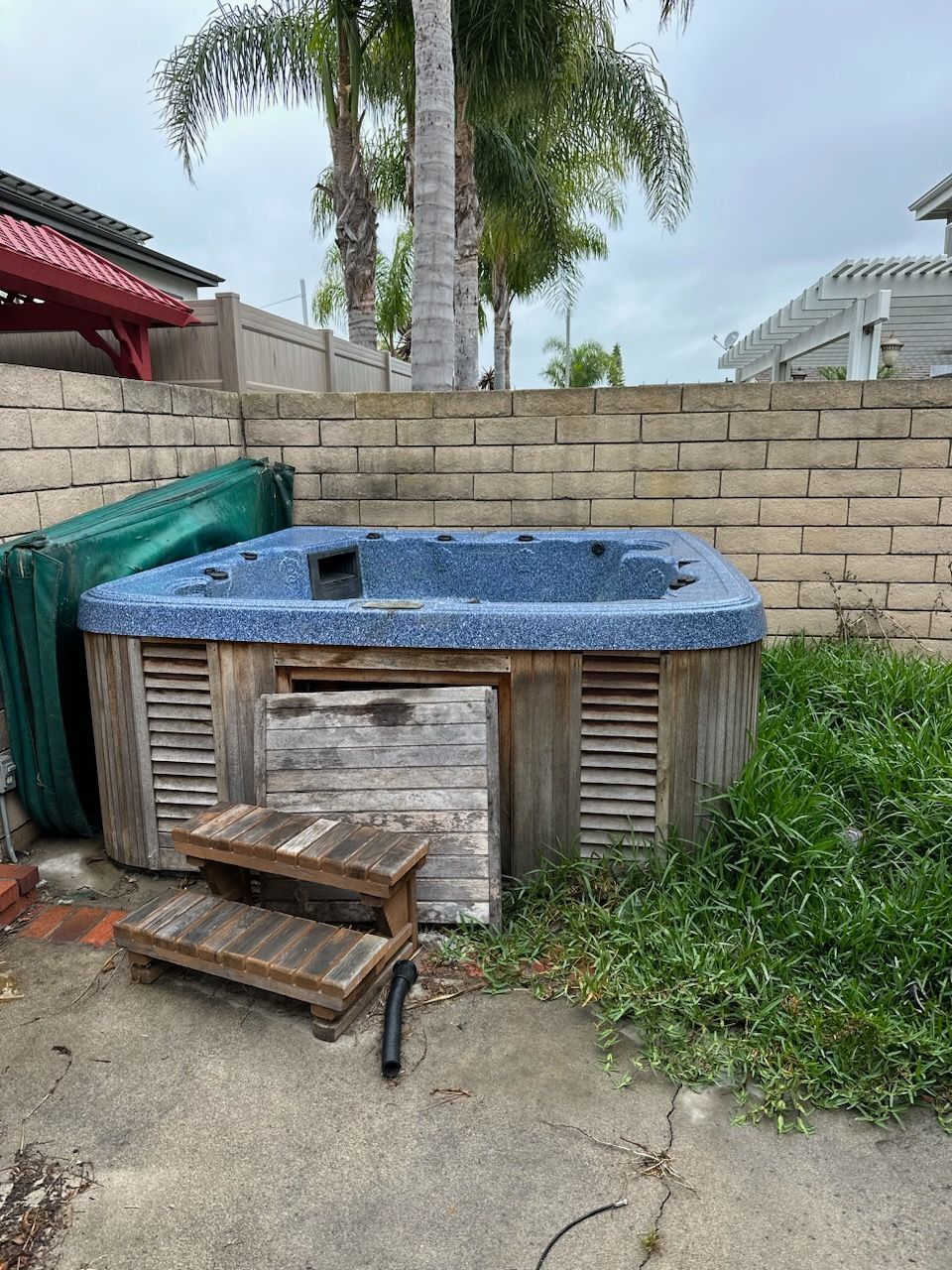 A hot tub is sitting on a concrete patio next to a brick wall.