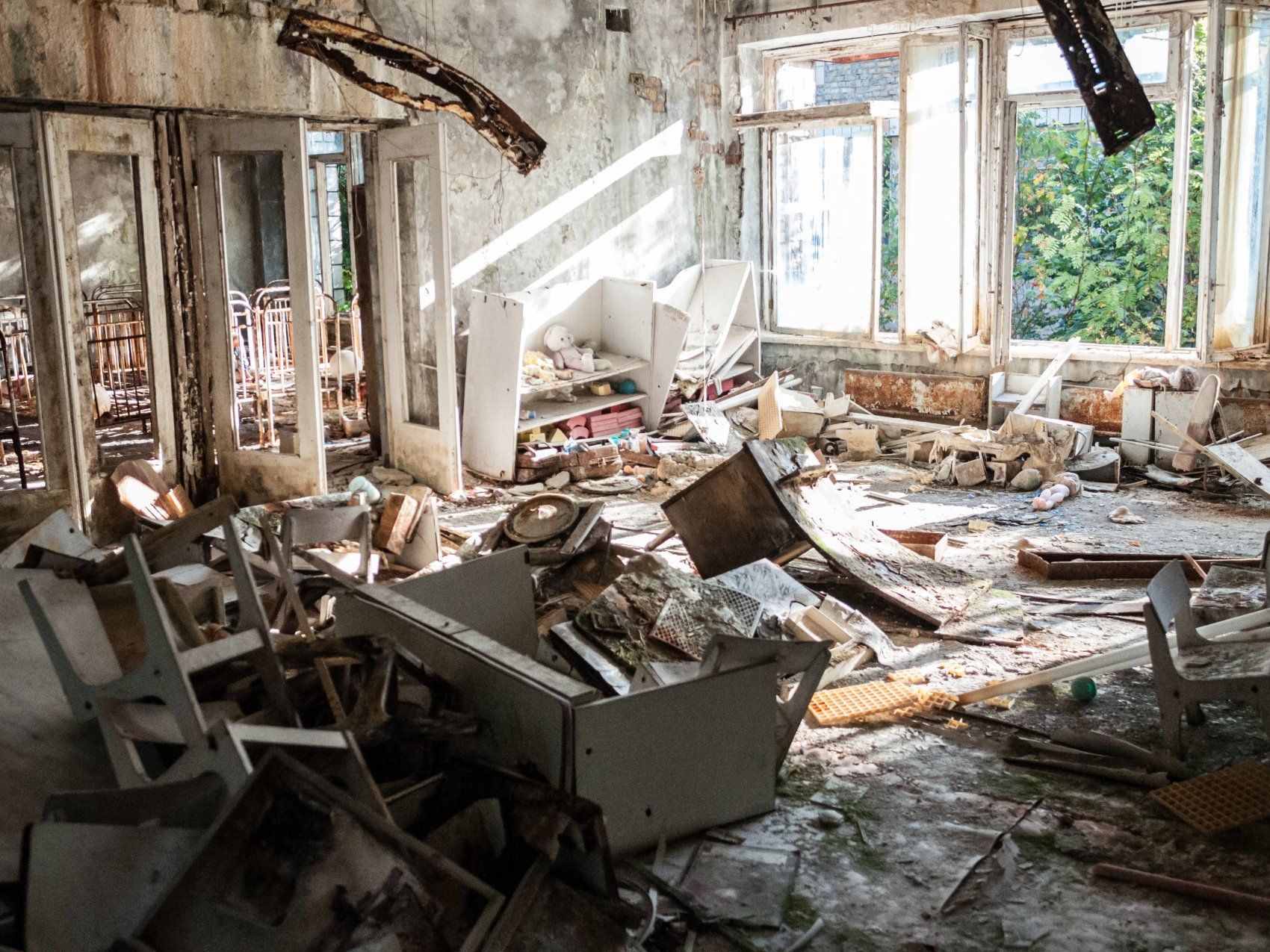 A room in an abandoned building with a lot of trash on the floor.