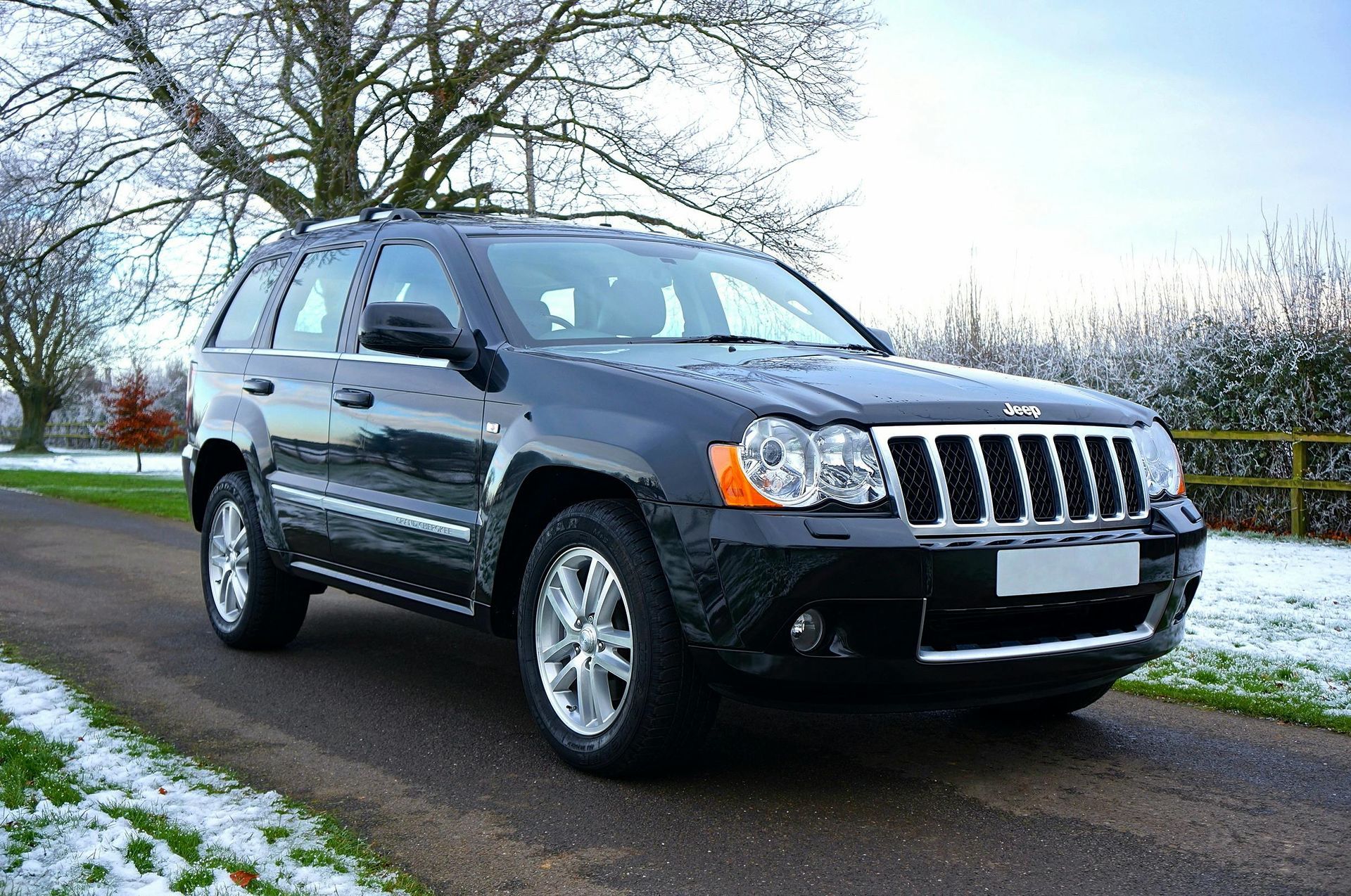 A black jeep grand cherokee is parked on a snowy road.
