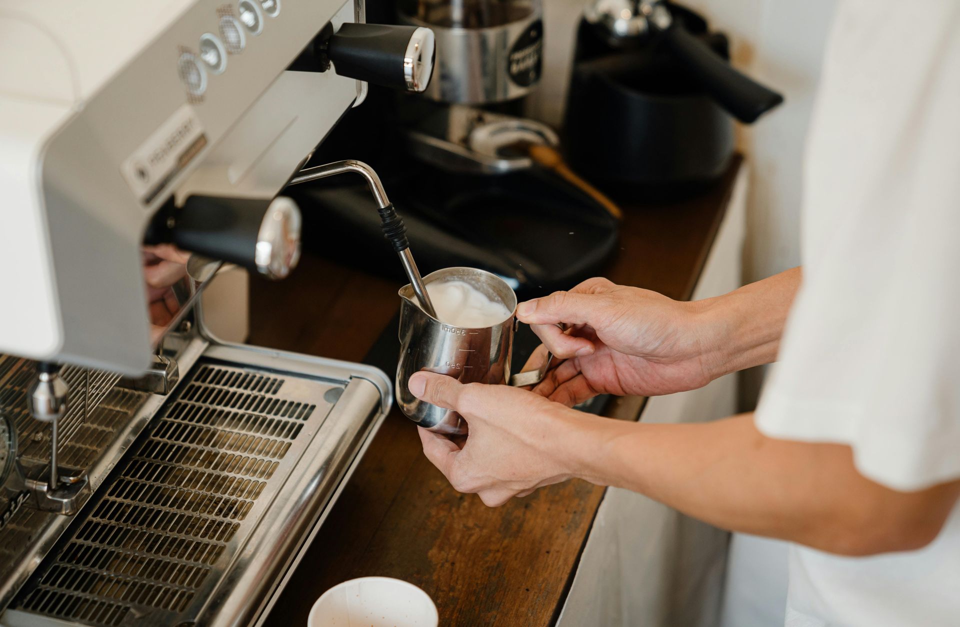 A person is pouring milk into a cup of coffee.
