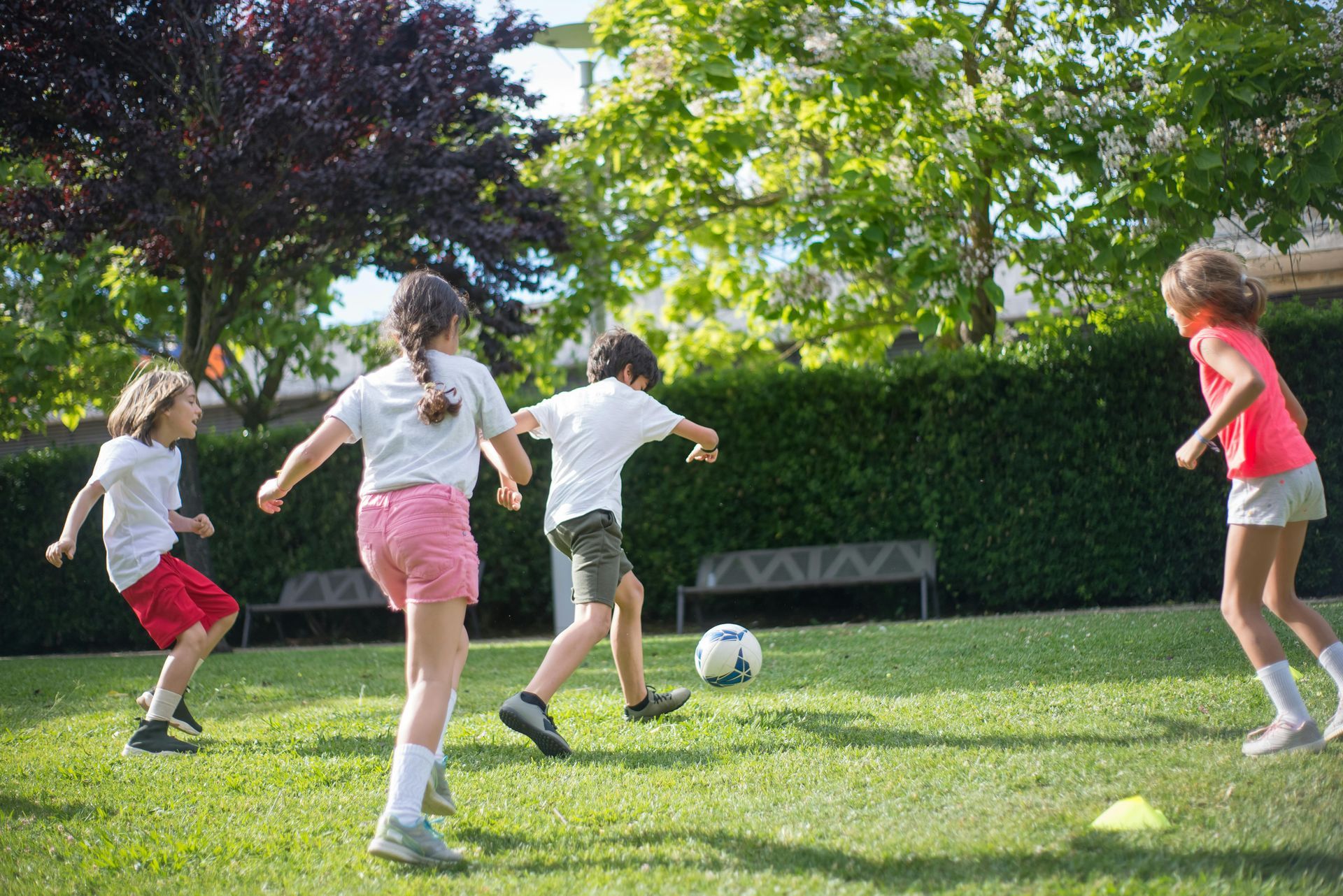 A group of children are playing soccer in a park.