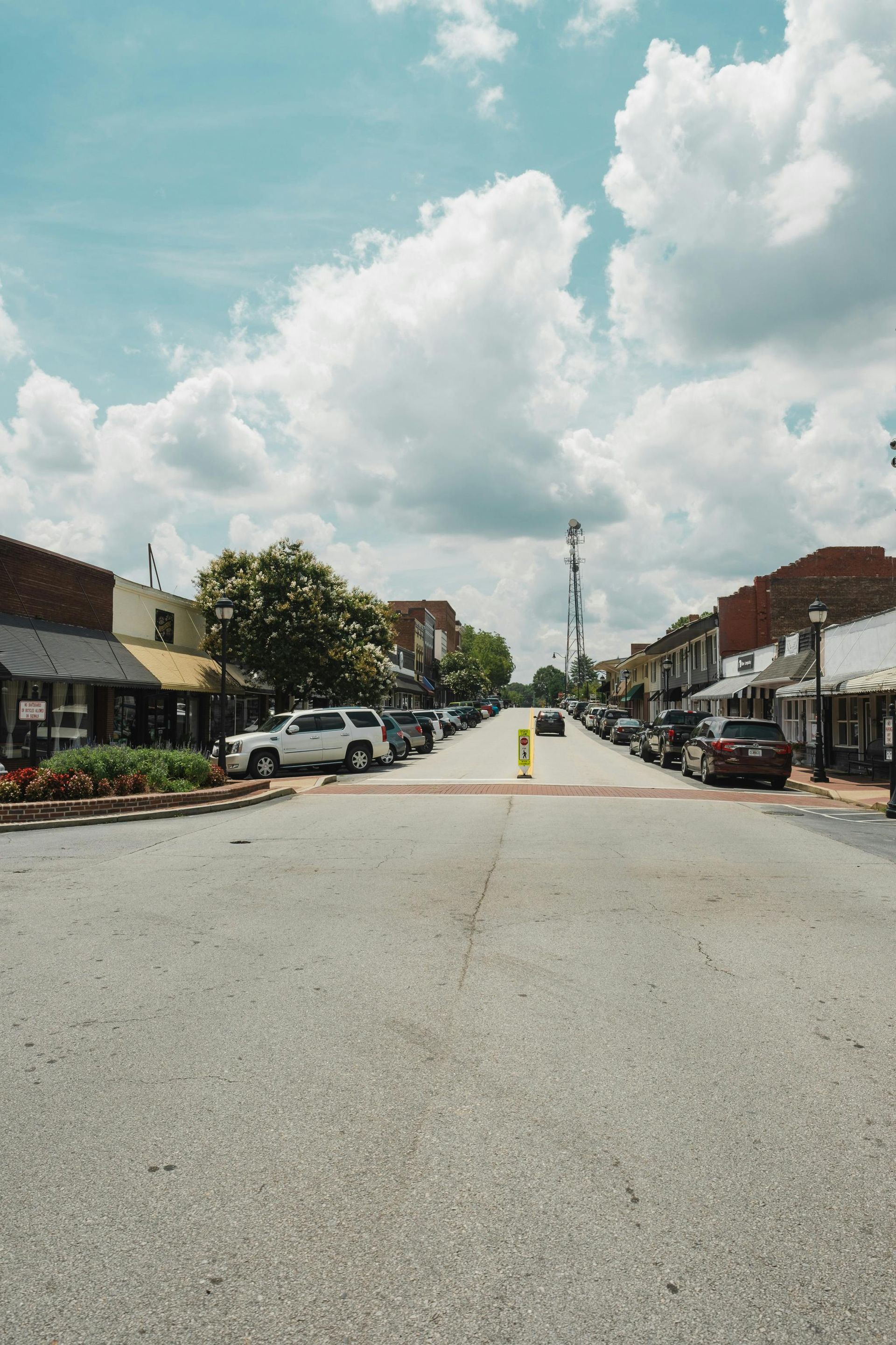 A small town street with a lot of cars parked on the side of the road.
