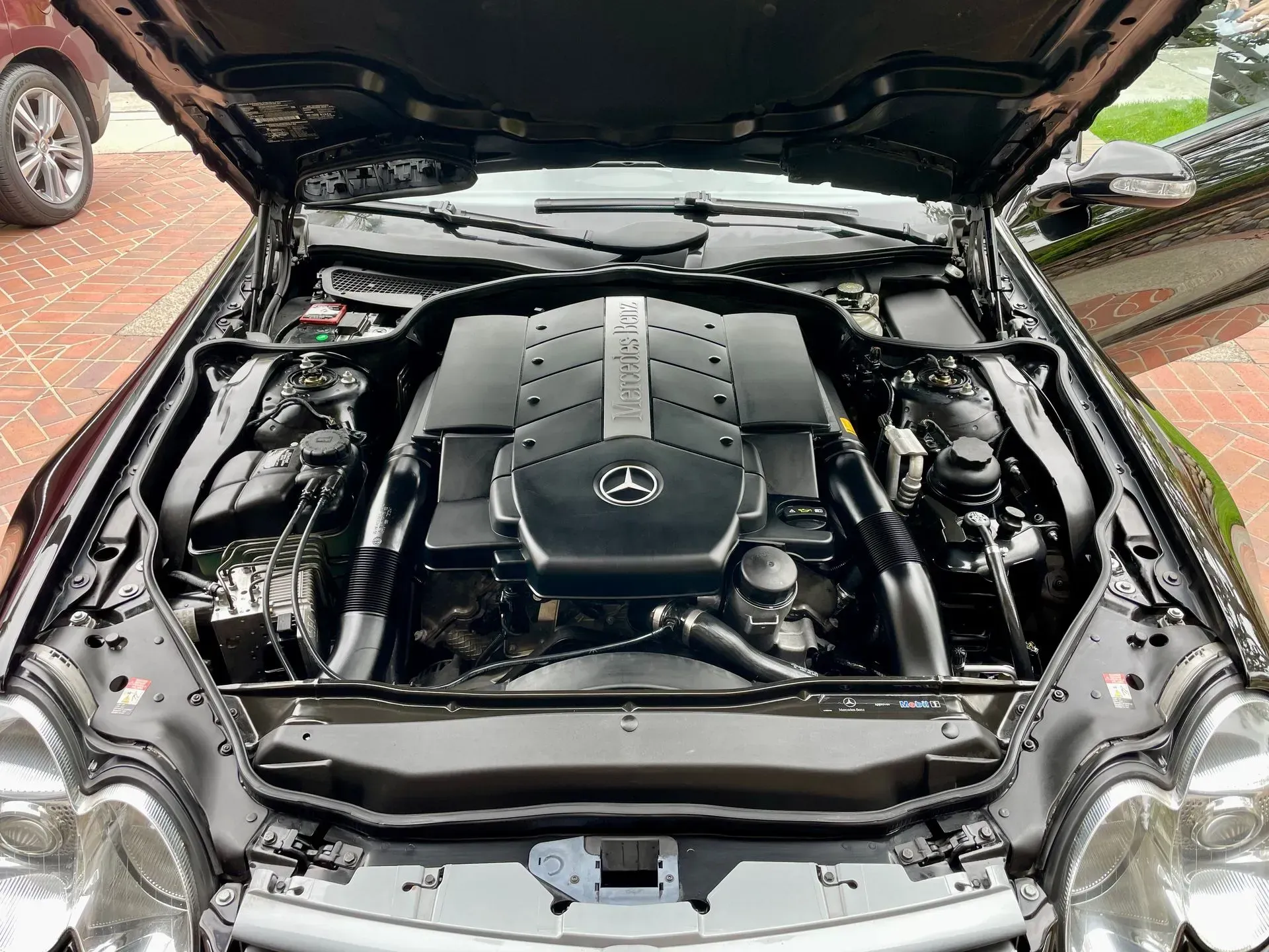 A clean Mercedes-Benz engine bay with a V8 engine cover visible under an open car hood.