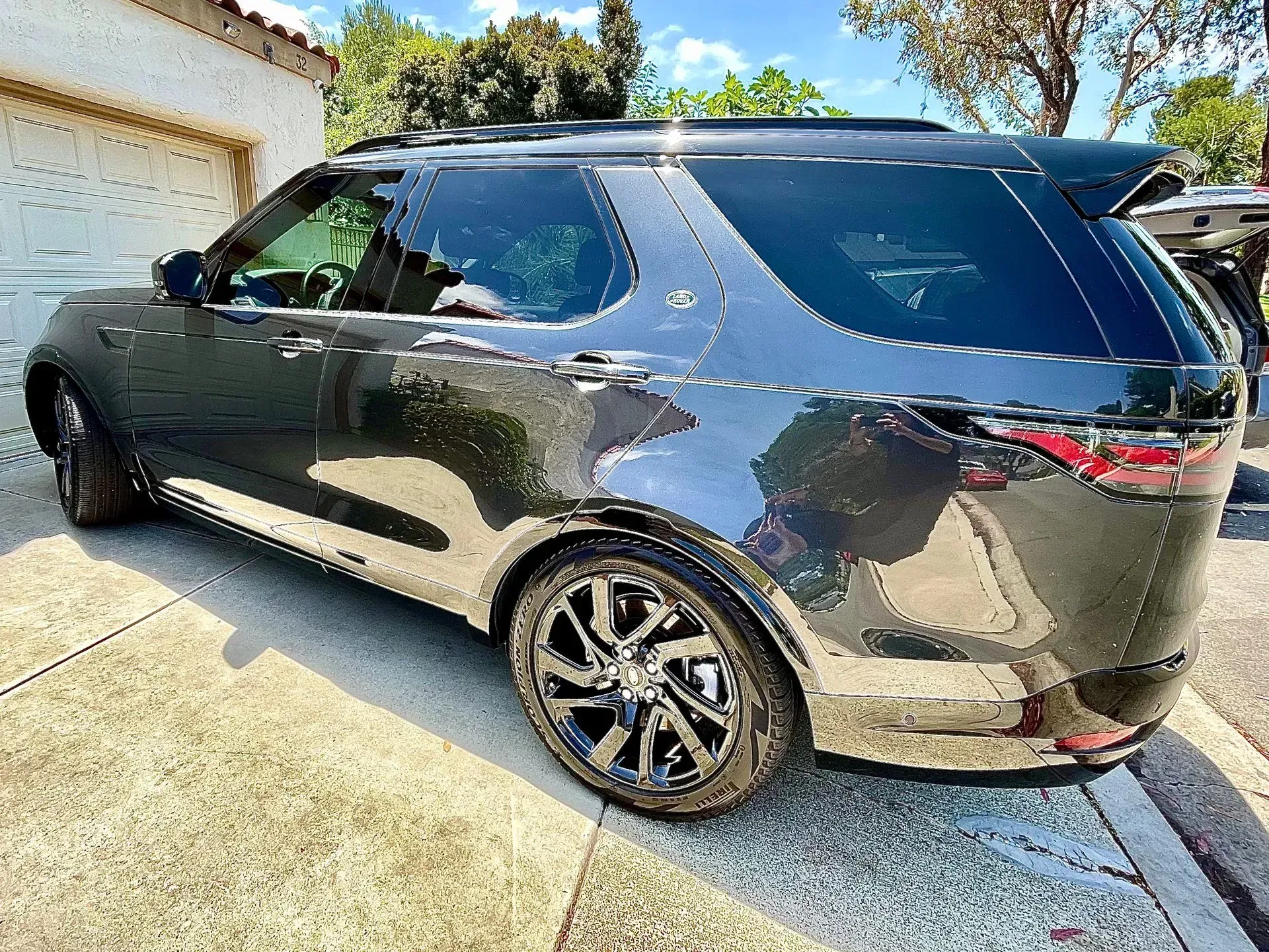 A dark gray Land Rover SUV parked on a paved driveway next to a white building.