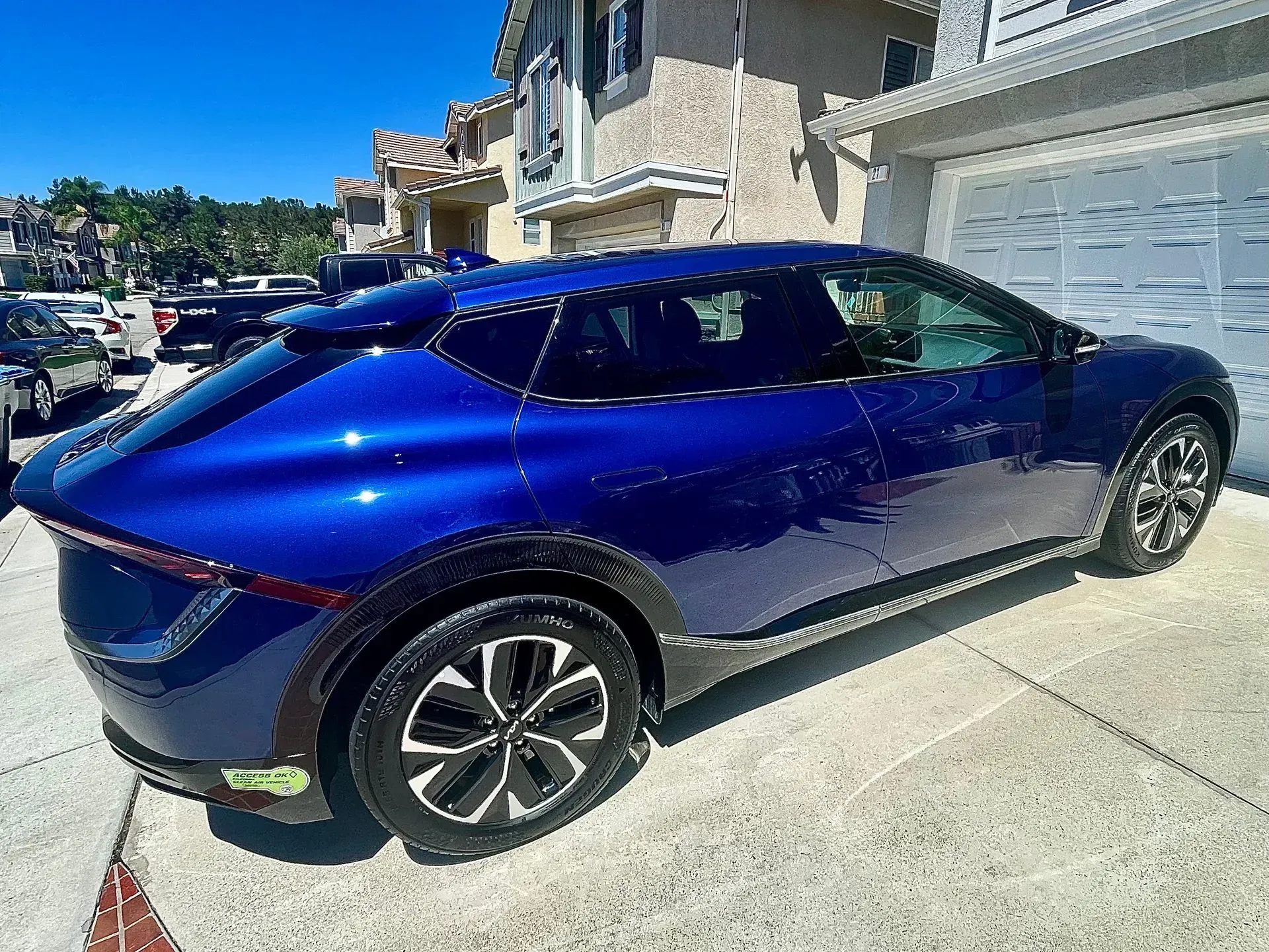 A deep blue Kia EV6 parked on a residential driveway on a sunny day.
