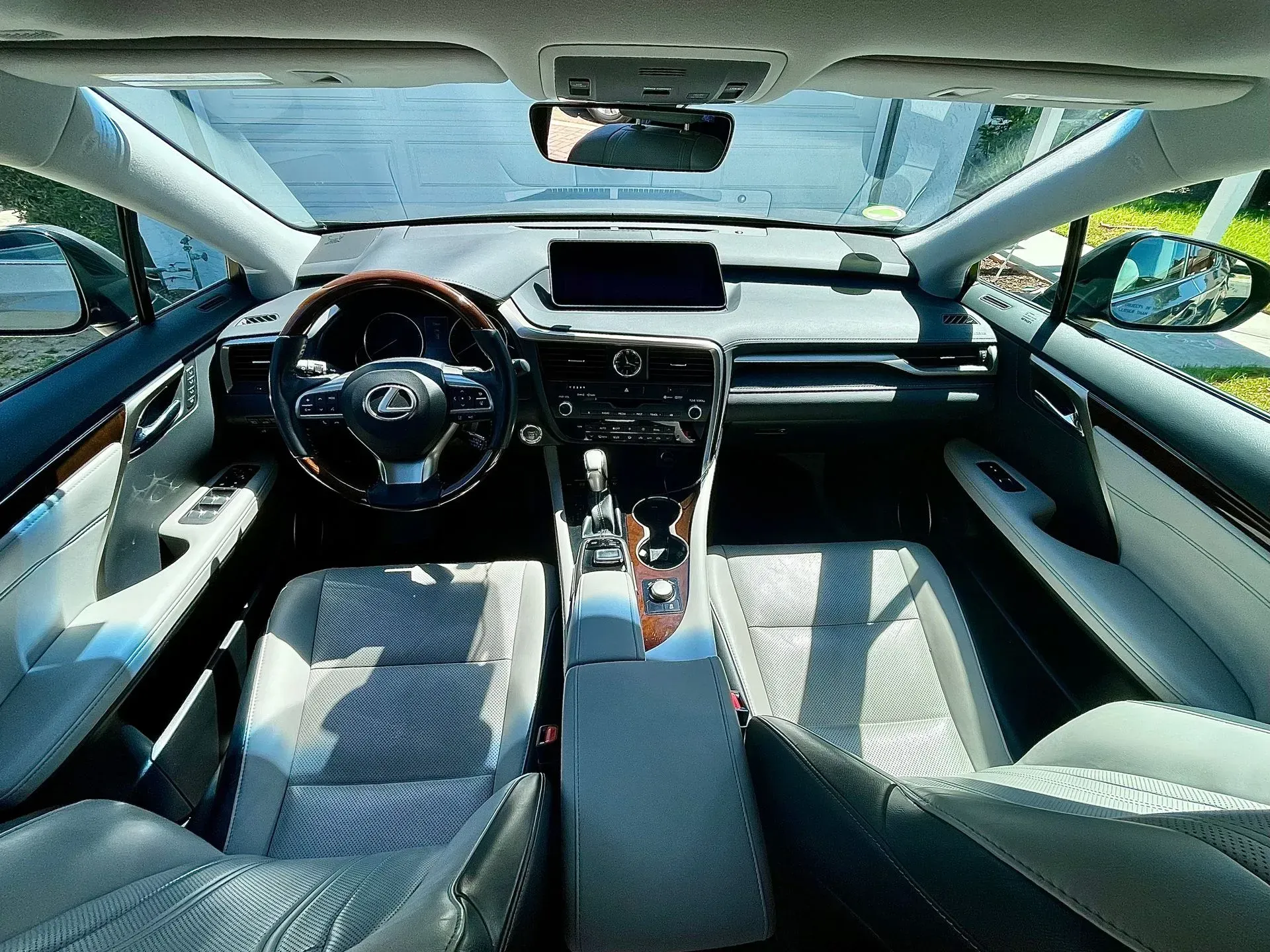 Interior view of a Lexus vehicle cabin, featuring a leather-wrapped steering wheel, dashboard screen, and light seats.