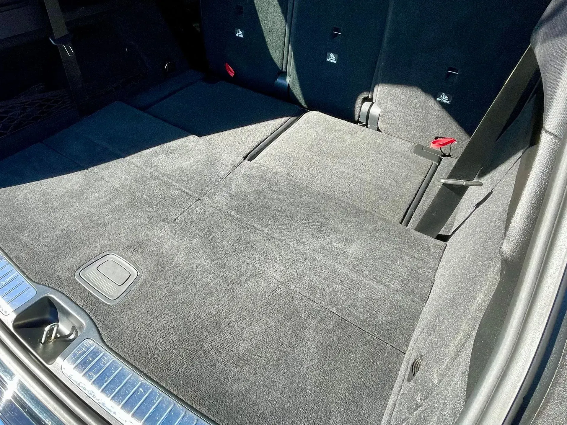 The interior of a vehicle trunk with carpeted floors and folded rear seats.