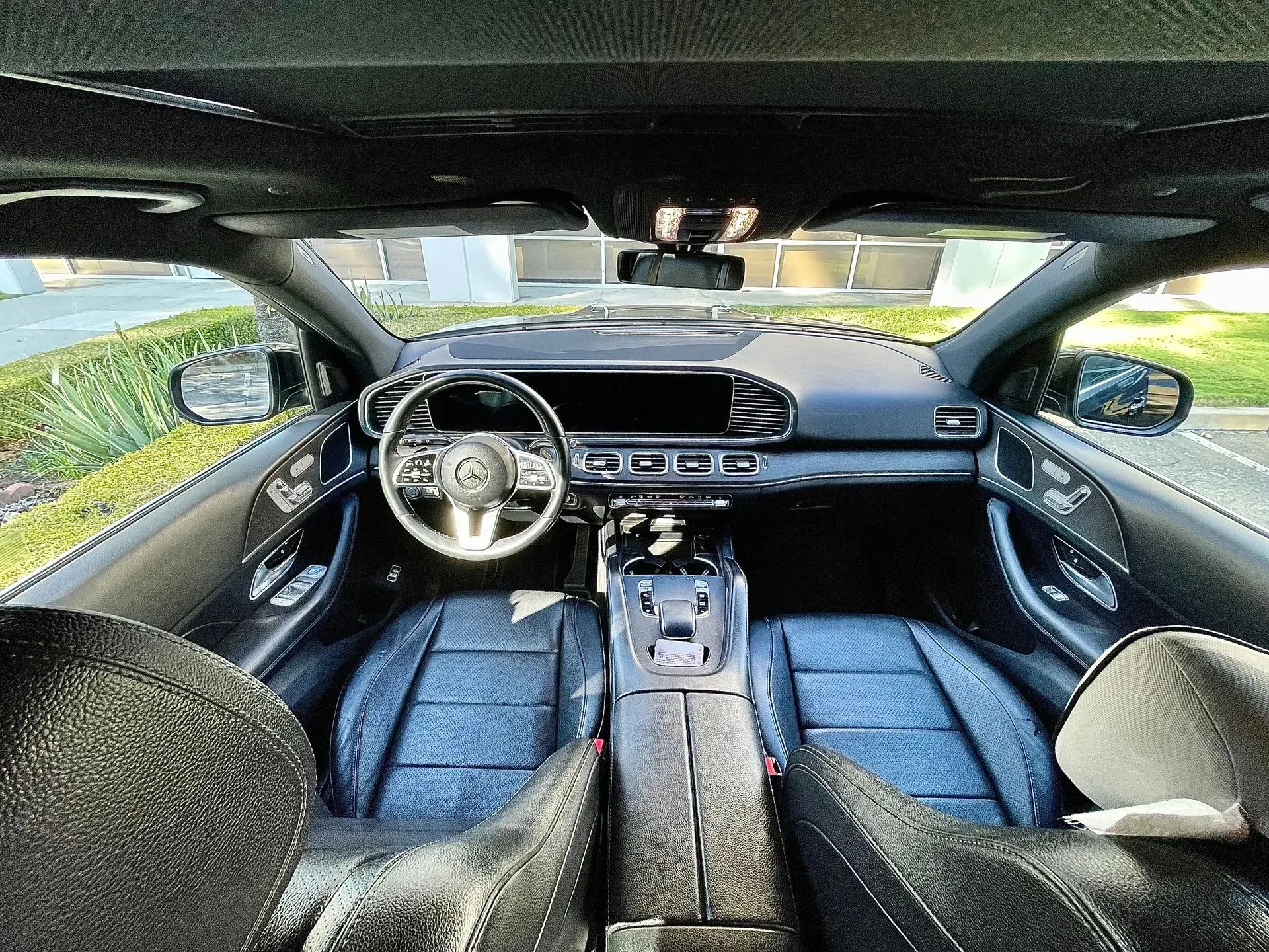 Interior view of a Mercedes-Benz car, featuring blue leather seats, a dark dashboard, and a steering wheel with the logo.
