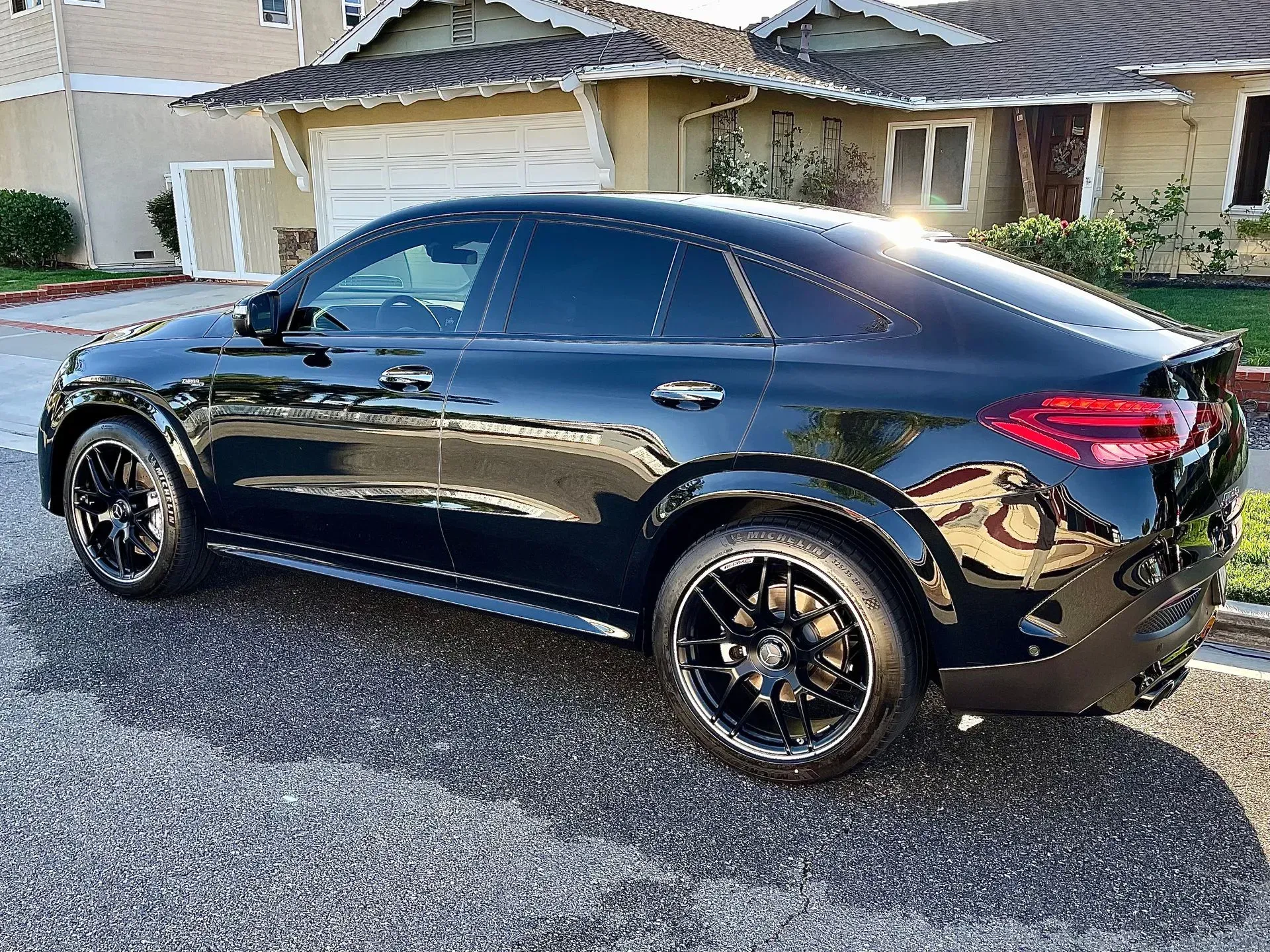 A black Mercedes-Benz SUV coupe parked on a residential driveway in front of a house.
