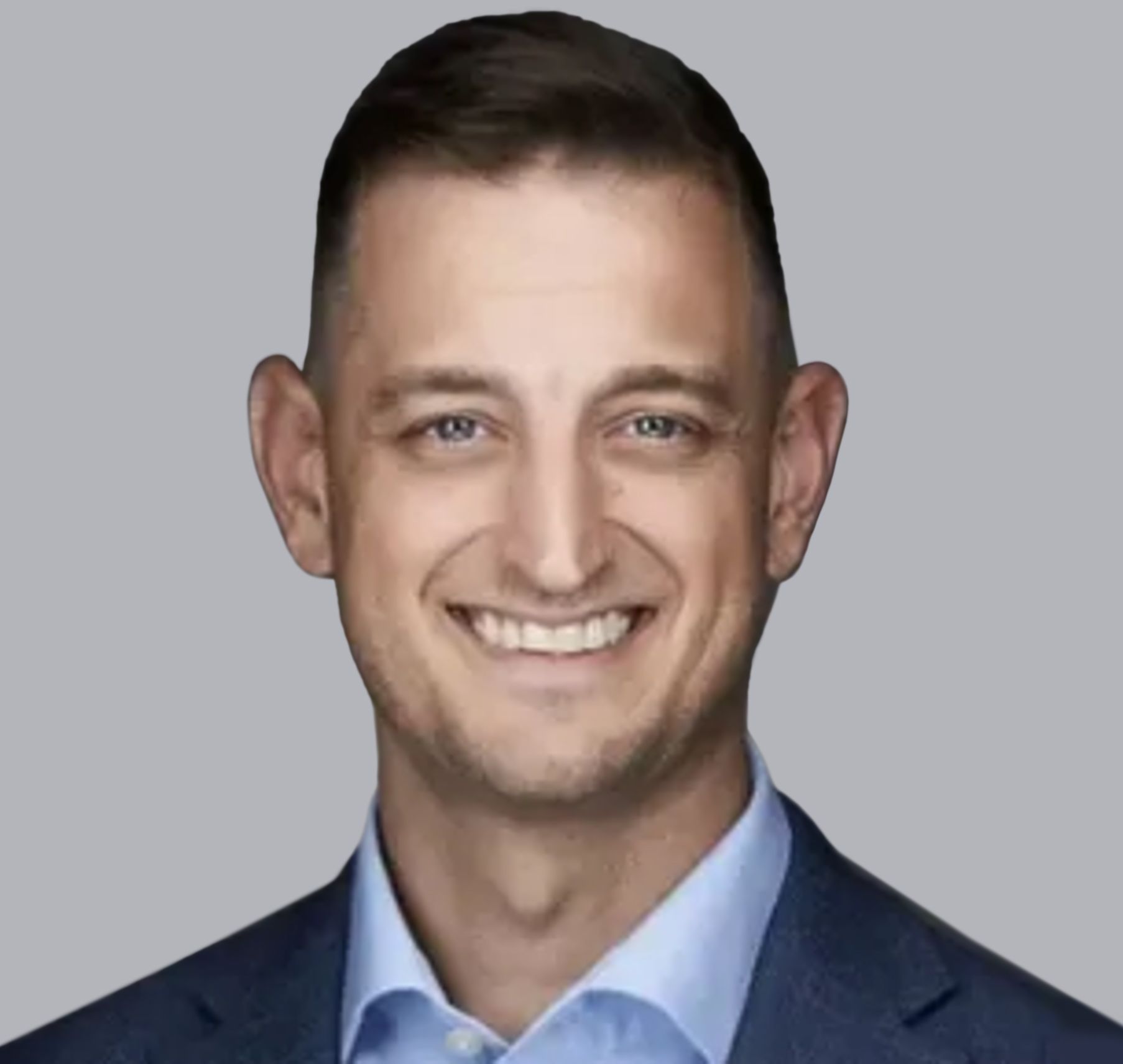 Smiling man in a blue suit and light blue shirt against a gray background.