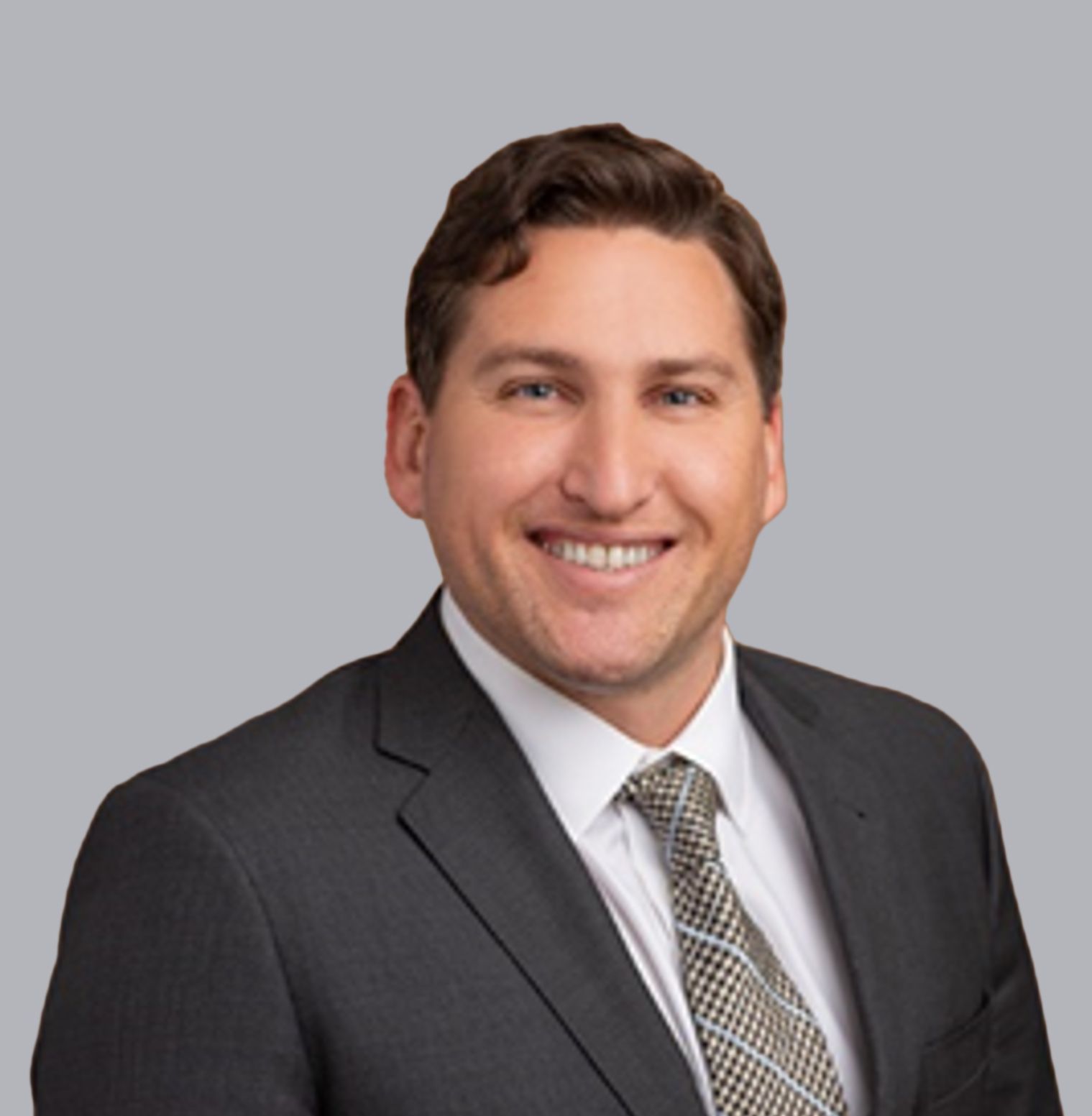 Man in suit, smiling, headshot against a gray background.