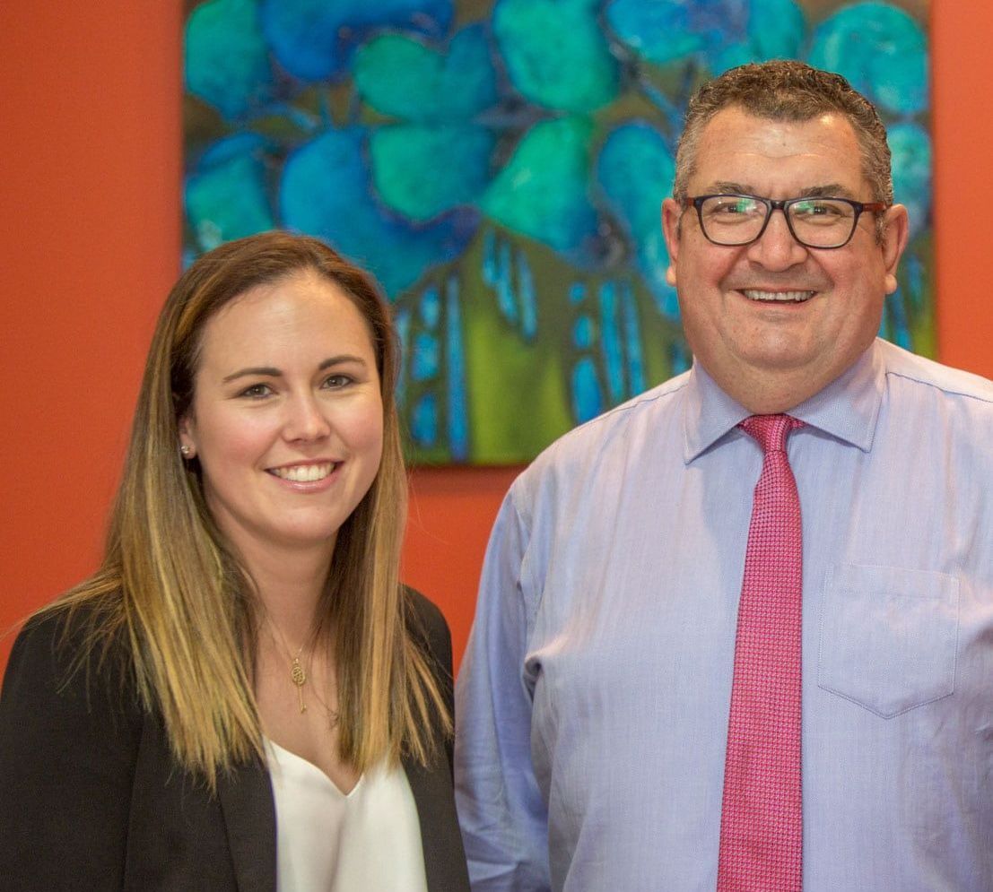 A Man And A Woman Are Posing For A Picture In Front Of A Painting — Saracens Financial Consultants In Alstonville, NSW