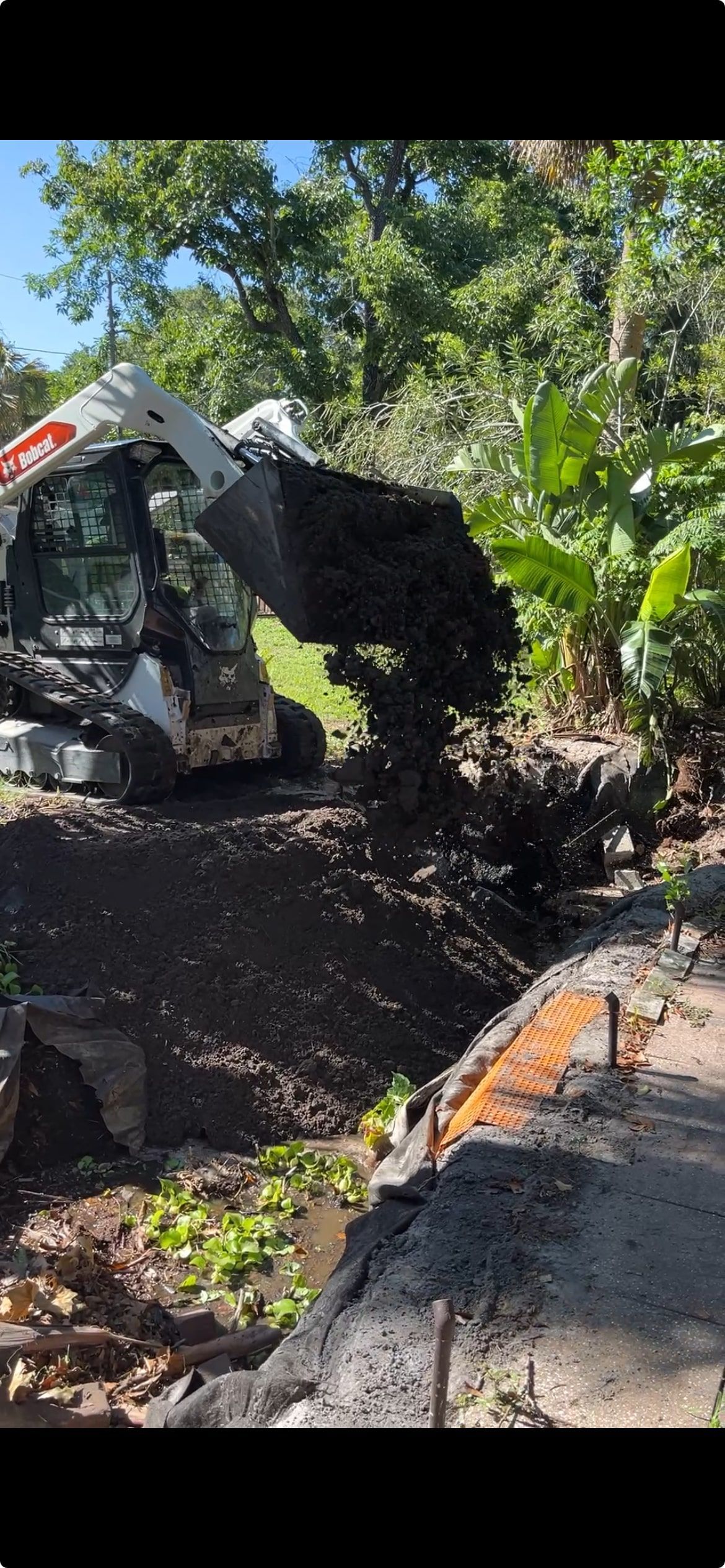 dirt being dropped into old pond by bobcat during demo