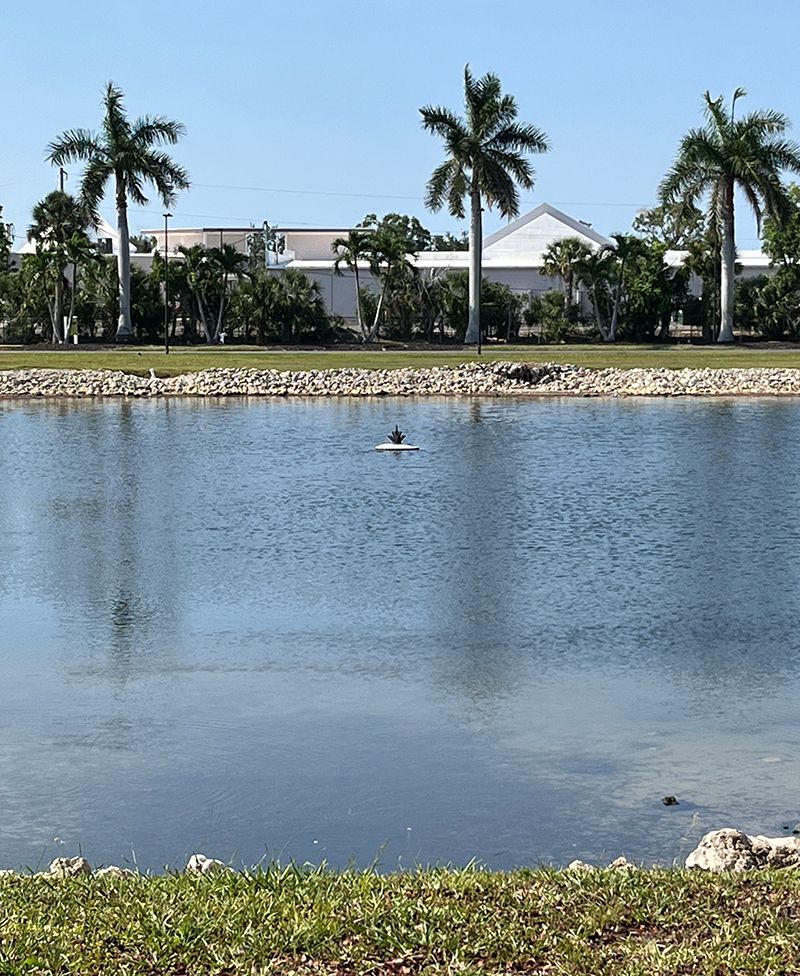 fountain with nozzle shown floating in a lake while not turned on