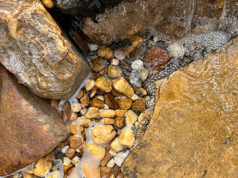 bubbling water spilling through large and small rocks on its way to the pond basin
