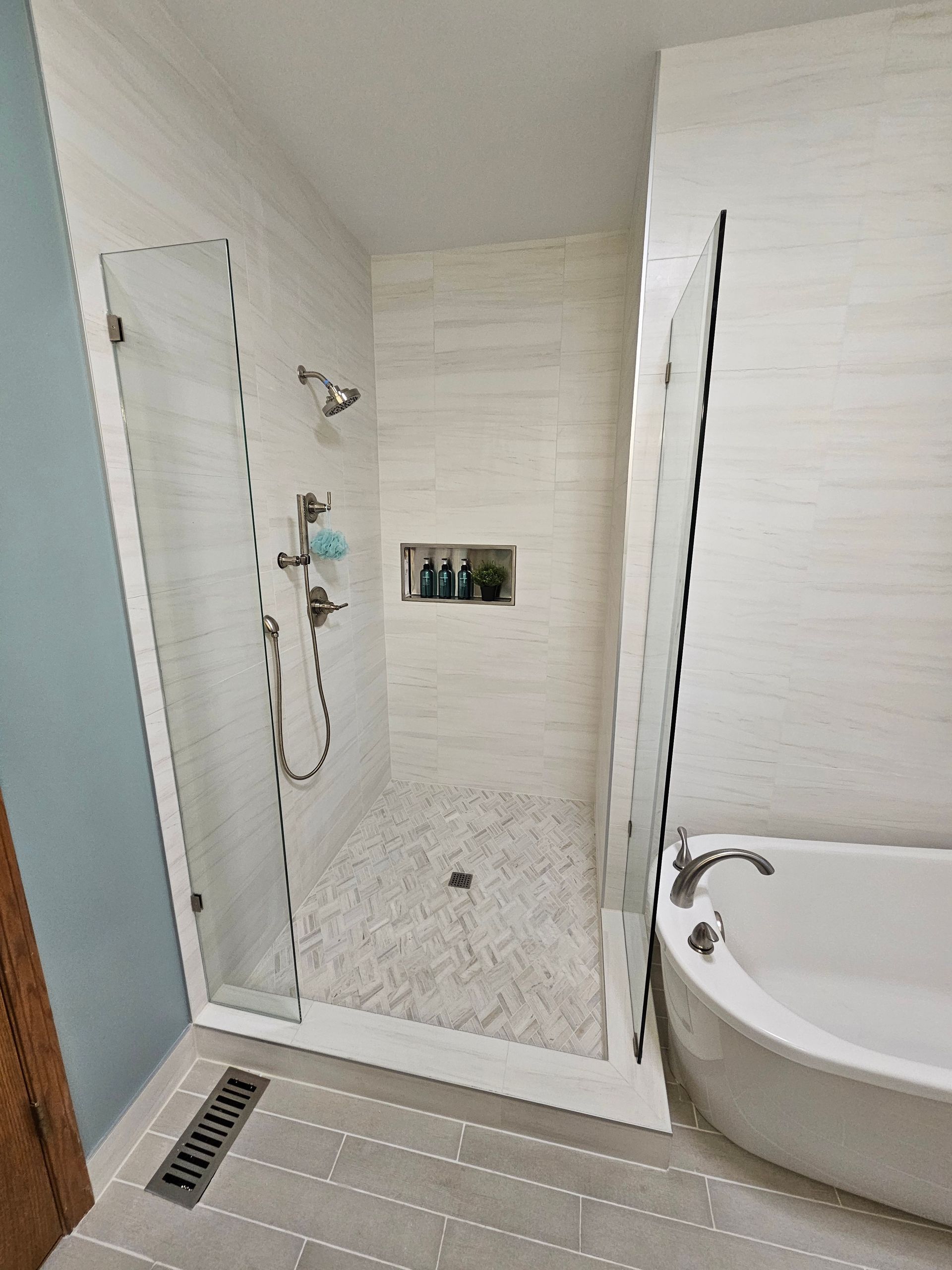 Modern bathroom with walk-in shower, white tile, glass doors, and bathtub.