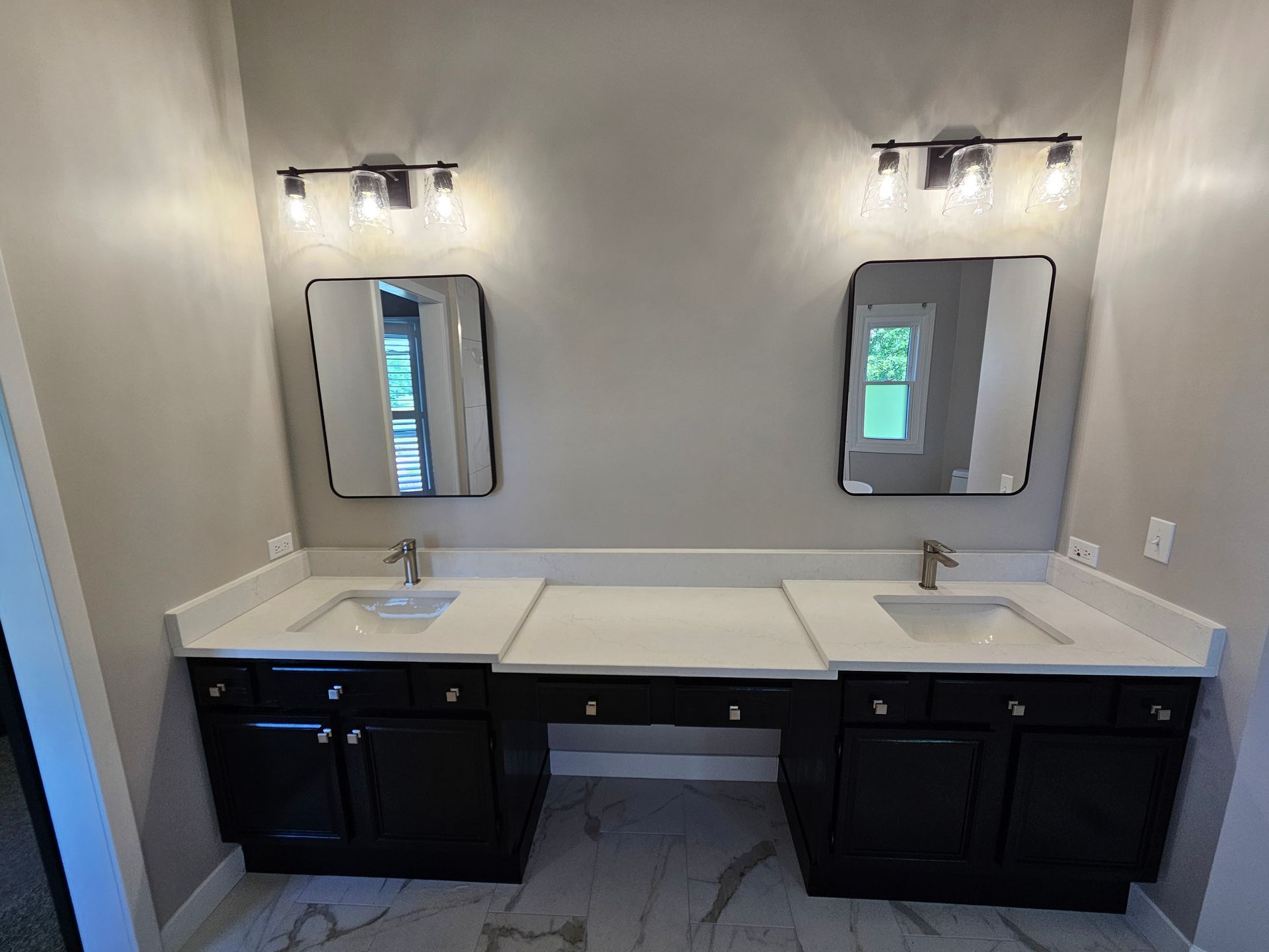 Black double vanity with mirrors and light fixtures in a bathroom.