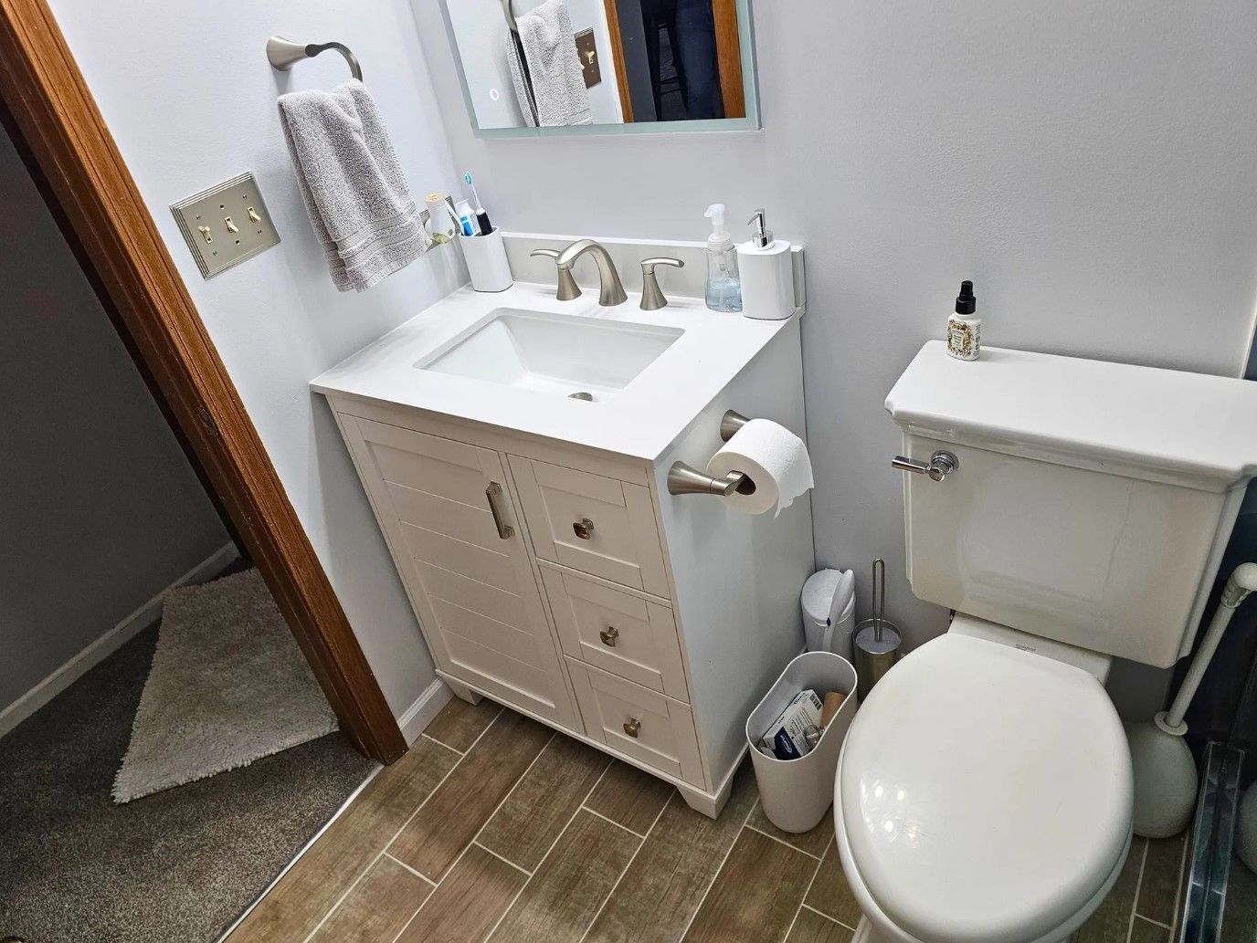 White bathroom with a sink, toilet, and cabinet; towel rack on the wall.