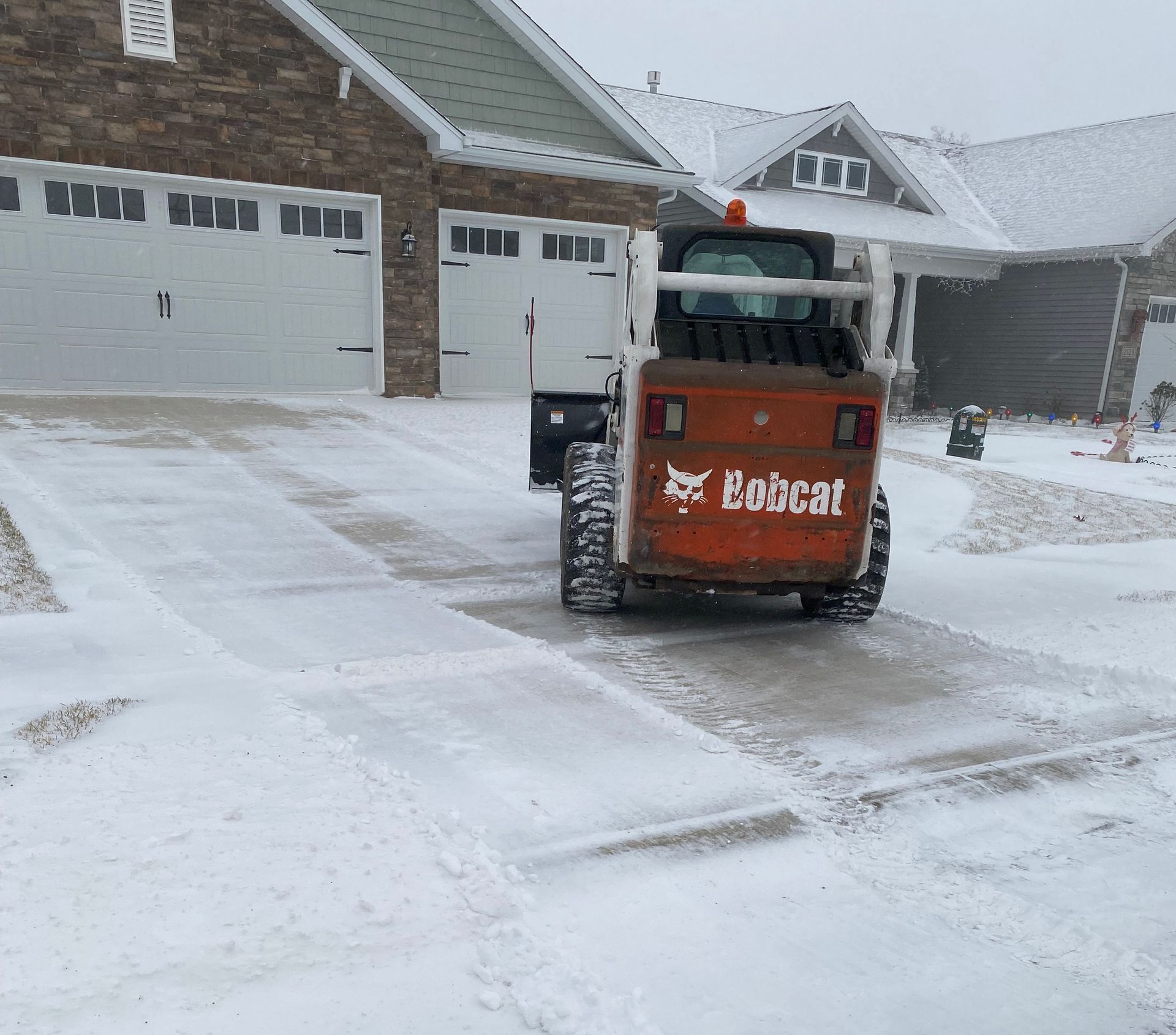 a bobcat brand excavator clearing snow from a driveway
